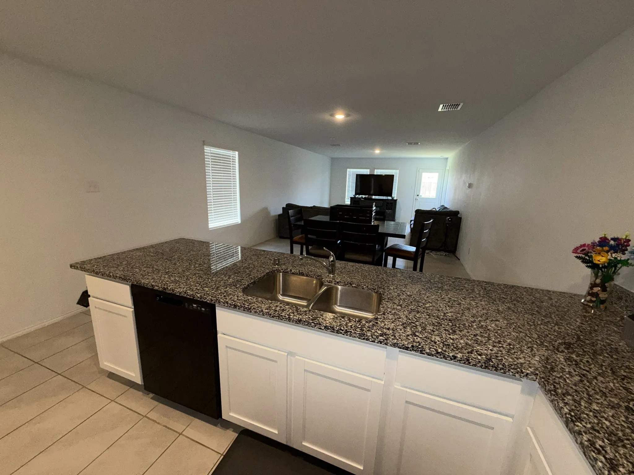 Kitchen island with speckled countertop, double-basin stainless steel sink, and integrated dishwasher