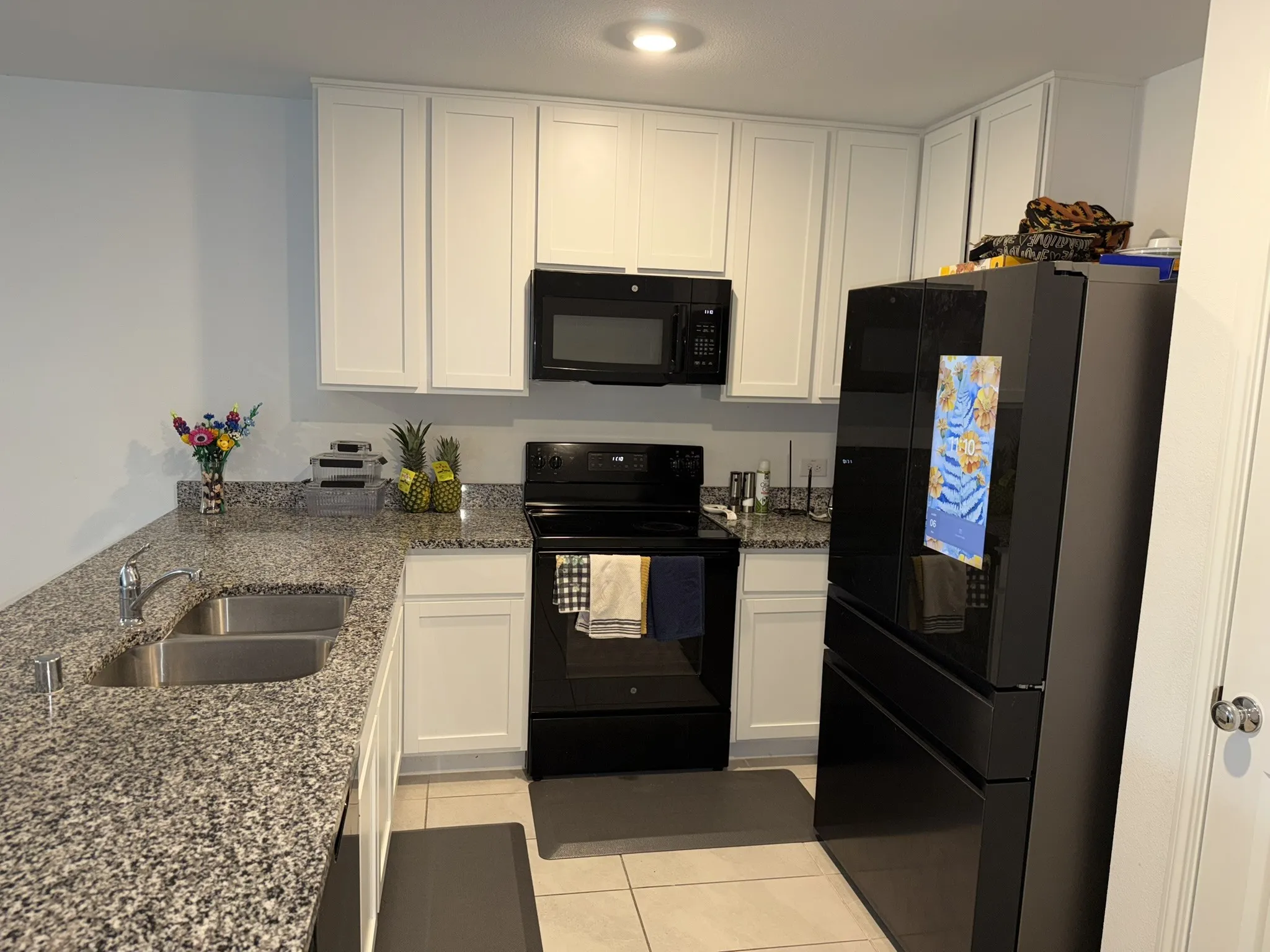 Kitchen featuring white shaker-style cabinetry, dark granite-look countertops, and stainless steel double basin sink