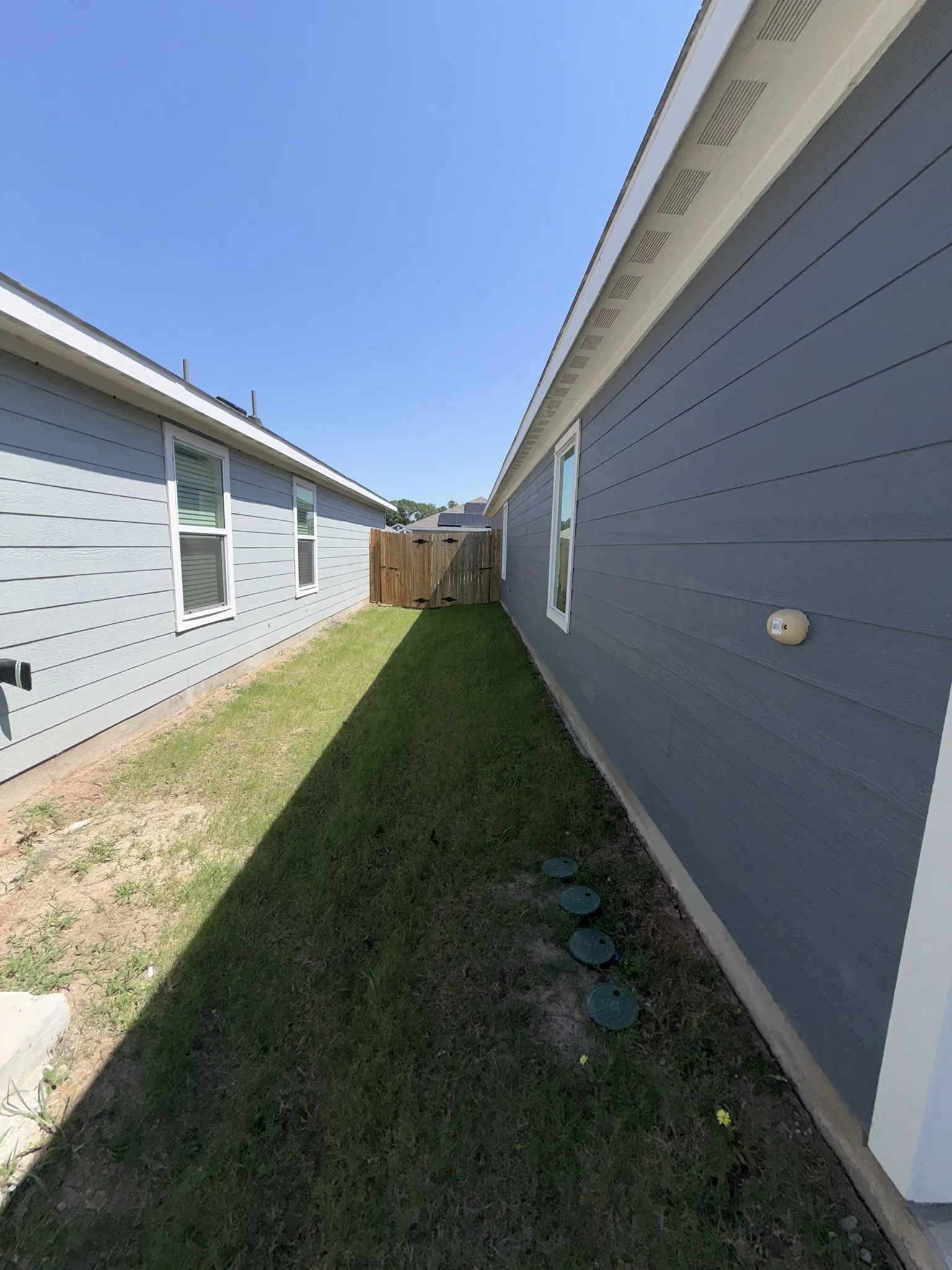 Side yard featuring a grass lawn, wood privacy fence, and light blue siding