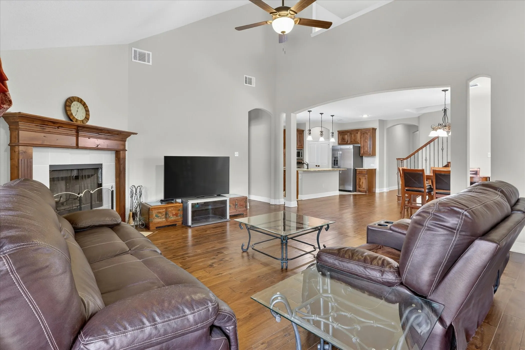 Spacious living area featuring wood-finish flooring, a vaulted ceiling, and a ceiling fan