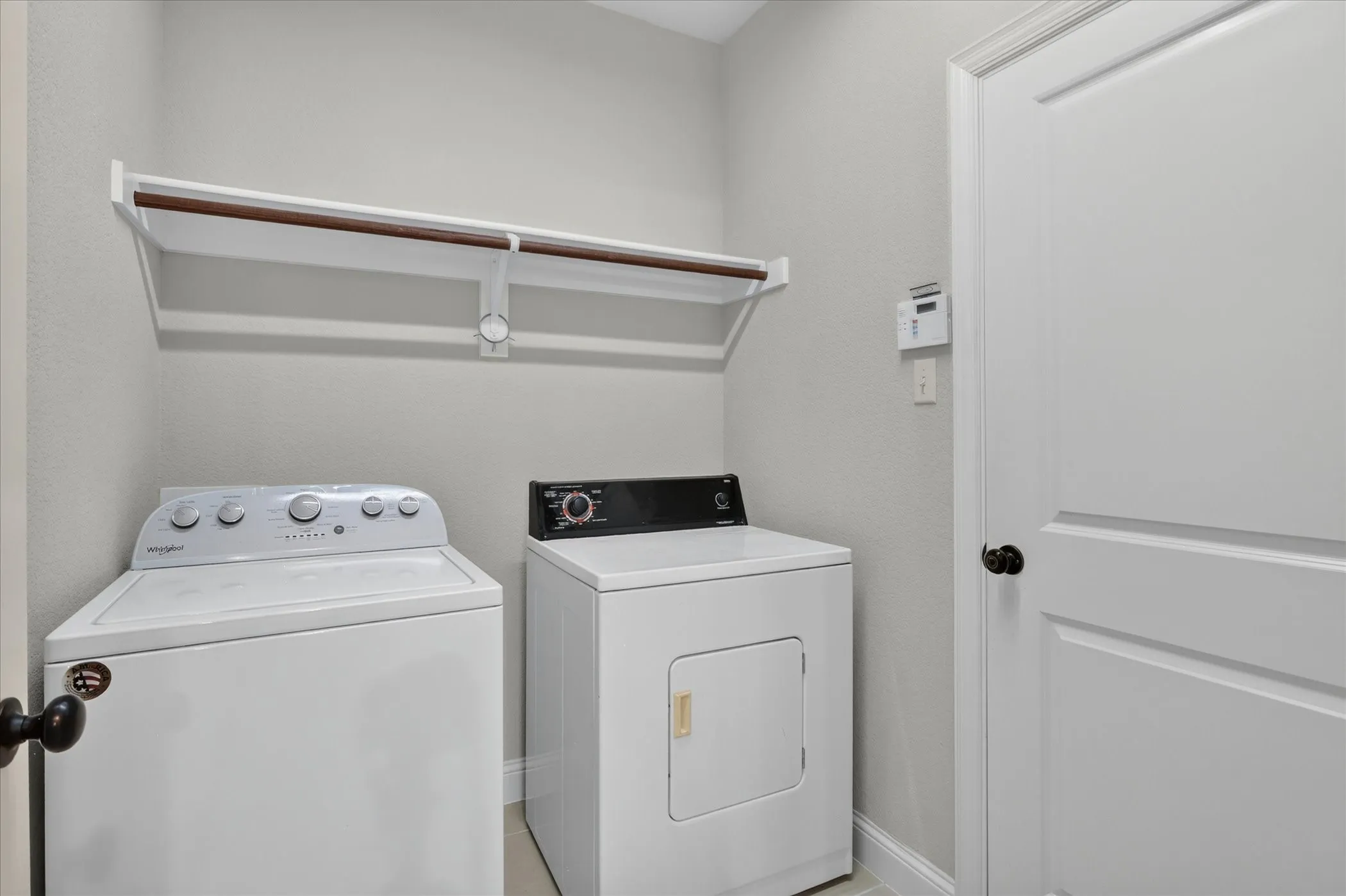 Dedicated utility space featuring a built-in hanging rod, wall-mounted shelving, and light gray wall paint