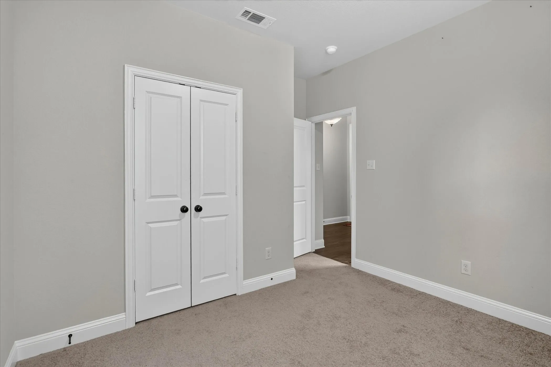Neutral-toned wall paint with white trim, featuring a double-door closet with black hardware