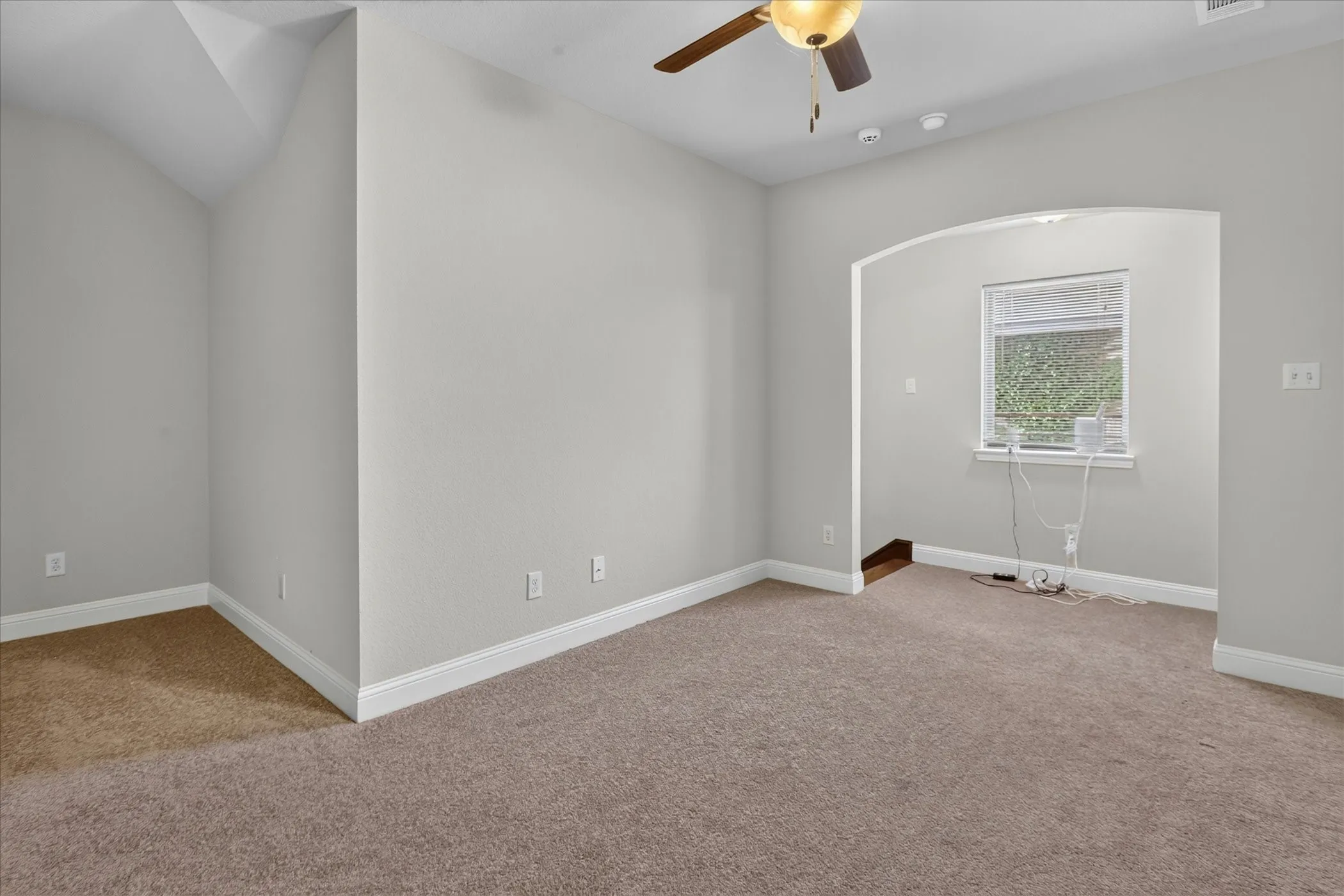 Carpeted interior space featuring an arched entryway, recessed lighting, and a ceiling fan