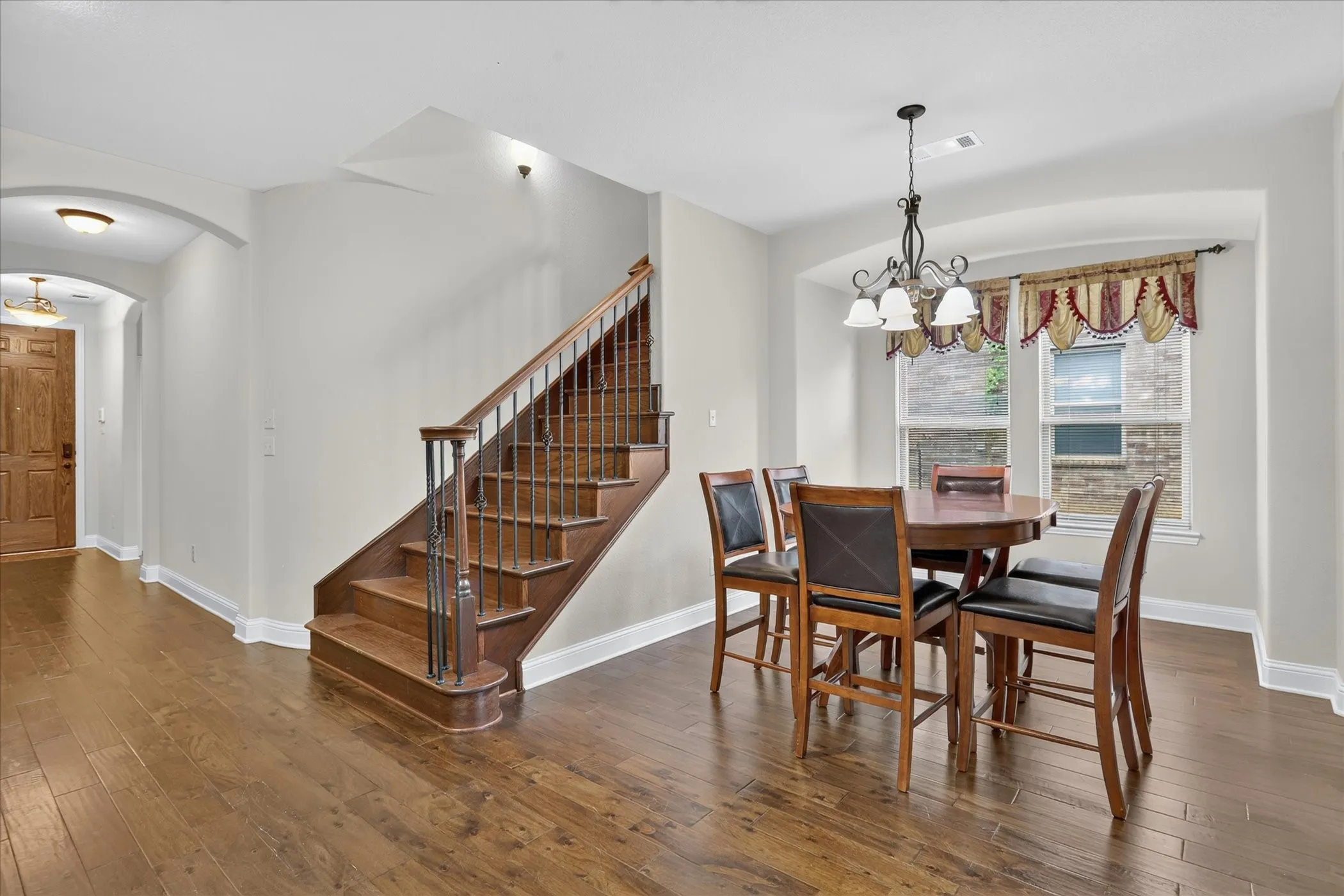 Hardwood-finish flooring throughout, featuring a turned staircase with wood treads and wrought iron balusters