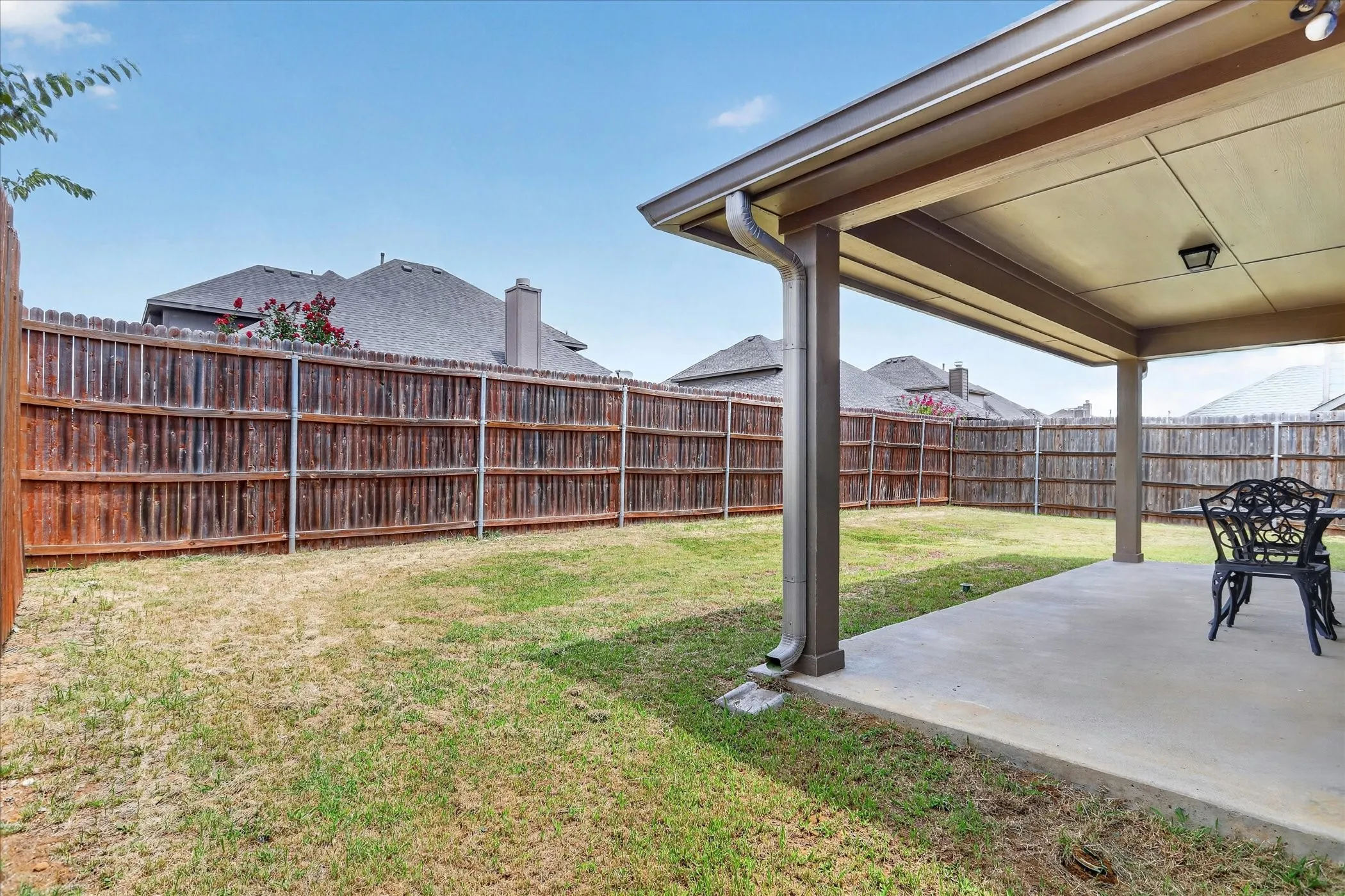 Expansive backyard with a covered patio featuring a concrete slab and overhead lighting