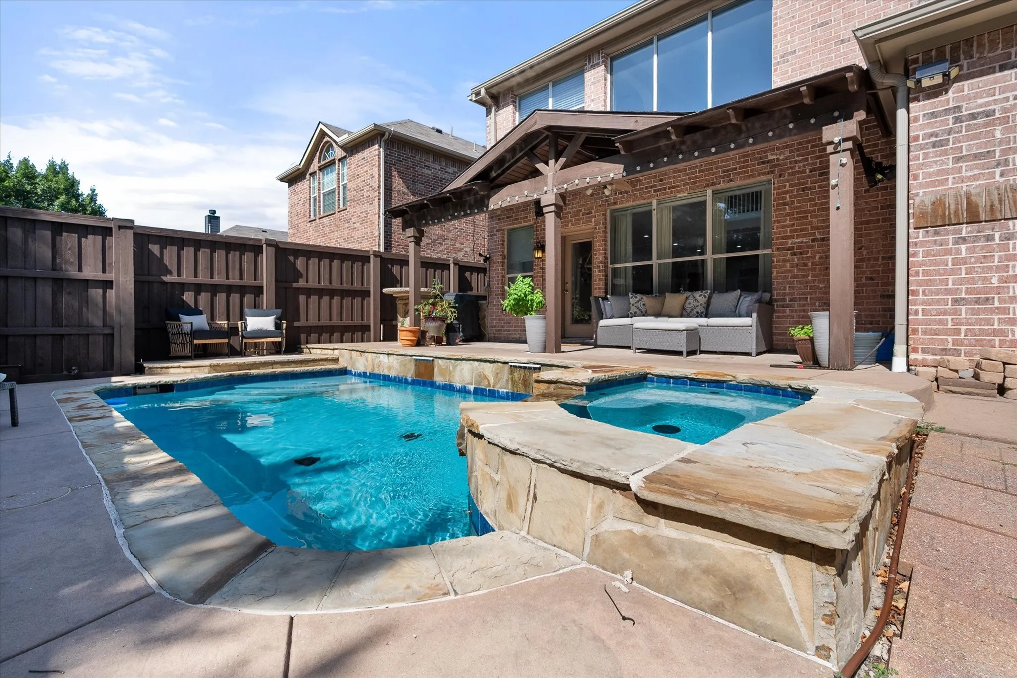 Outdoor entertaining area featuring a rectangular pool with integrated spa and stone coping!