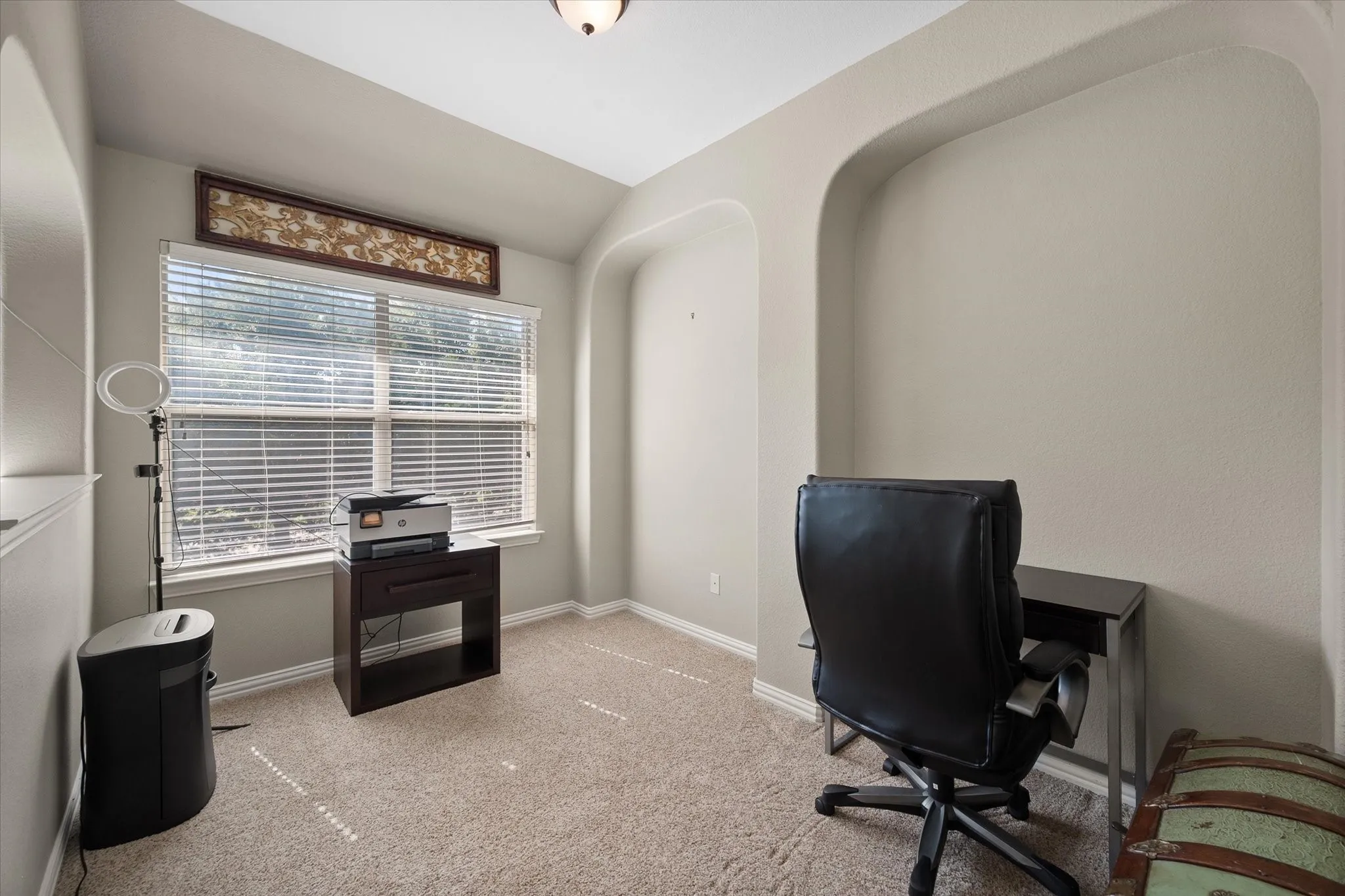 Carpeted room featuring a large window with blinds, recessed wall alcoves, and a ceiling light fixture