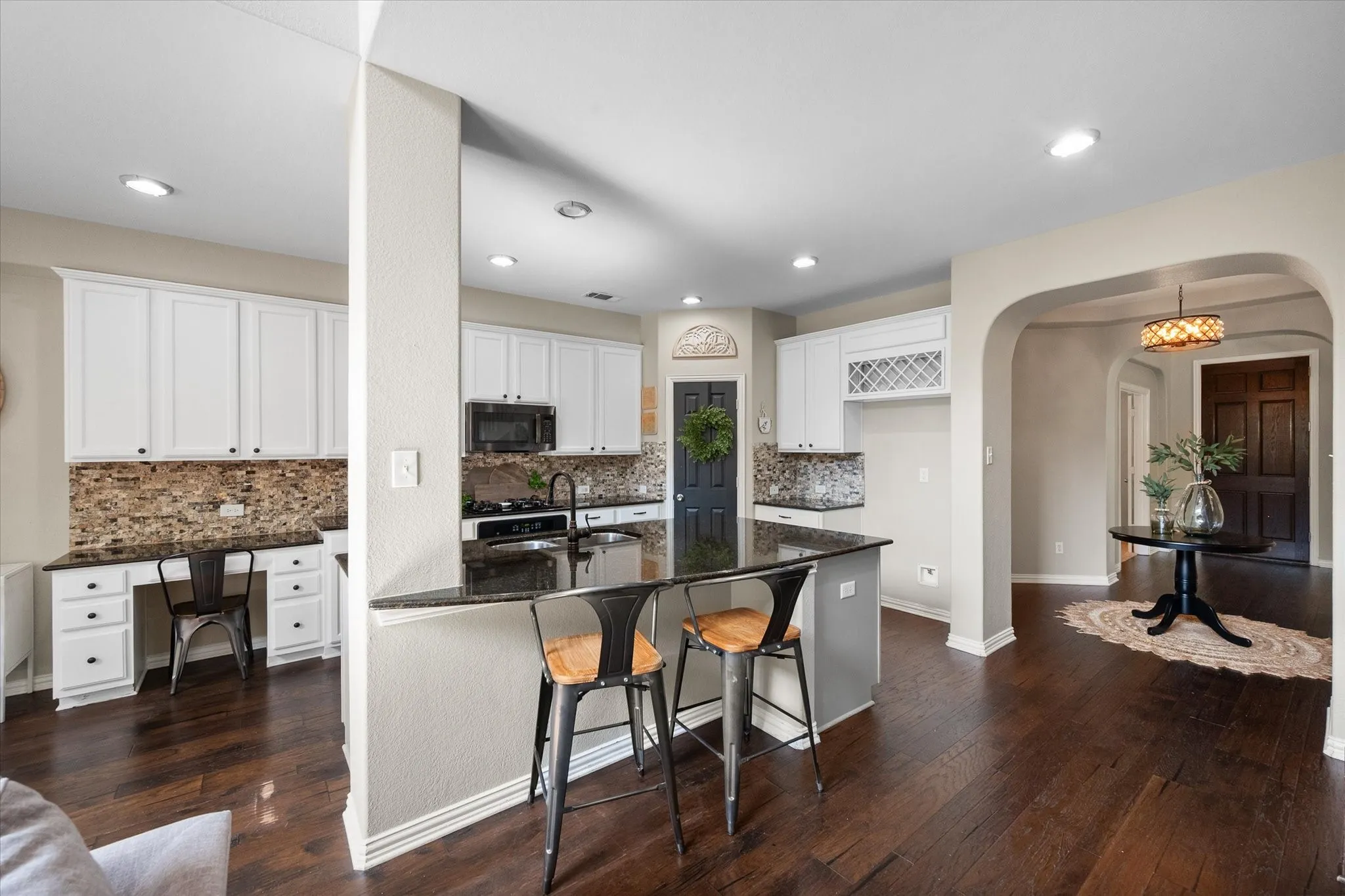 Kitchen with a built-in desk, custom cabinetry, granite  countertops, and mosaic tile backsplash and pantry!