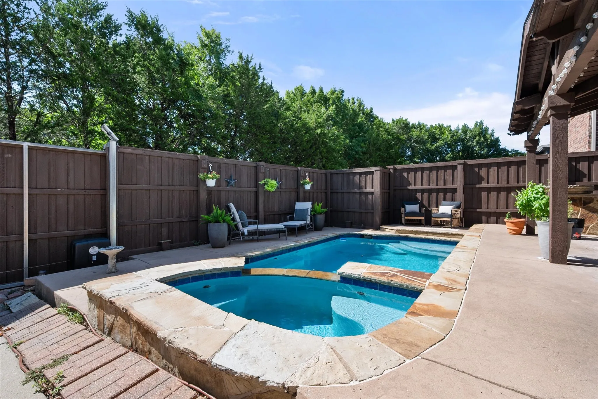 Private fence surrounds the swimming pool with an integrated spa, stone coping and concrete patio!