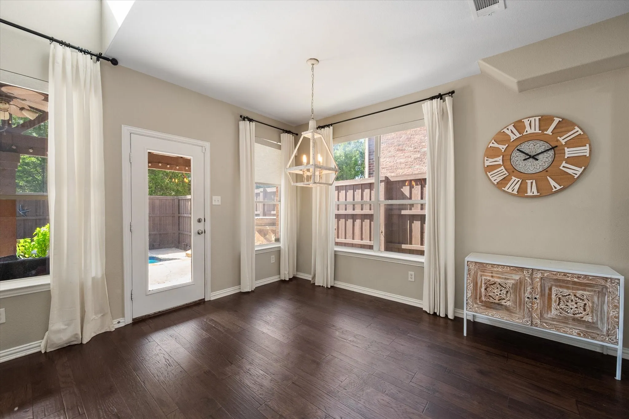Spacious breakfast nook, glass-paneled exterior door, and a geometric pendant light fixture overlooking the backyard!
