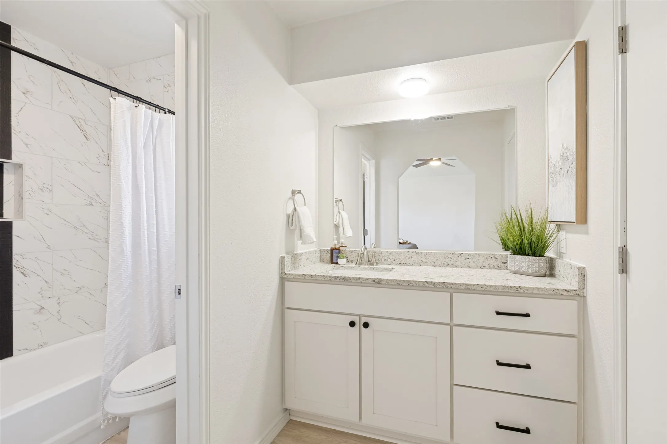Bathroom featuring a white vanity with a light-toned speckled countertop, an undermount sink, and black hardware