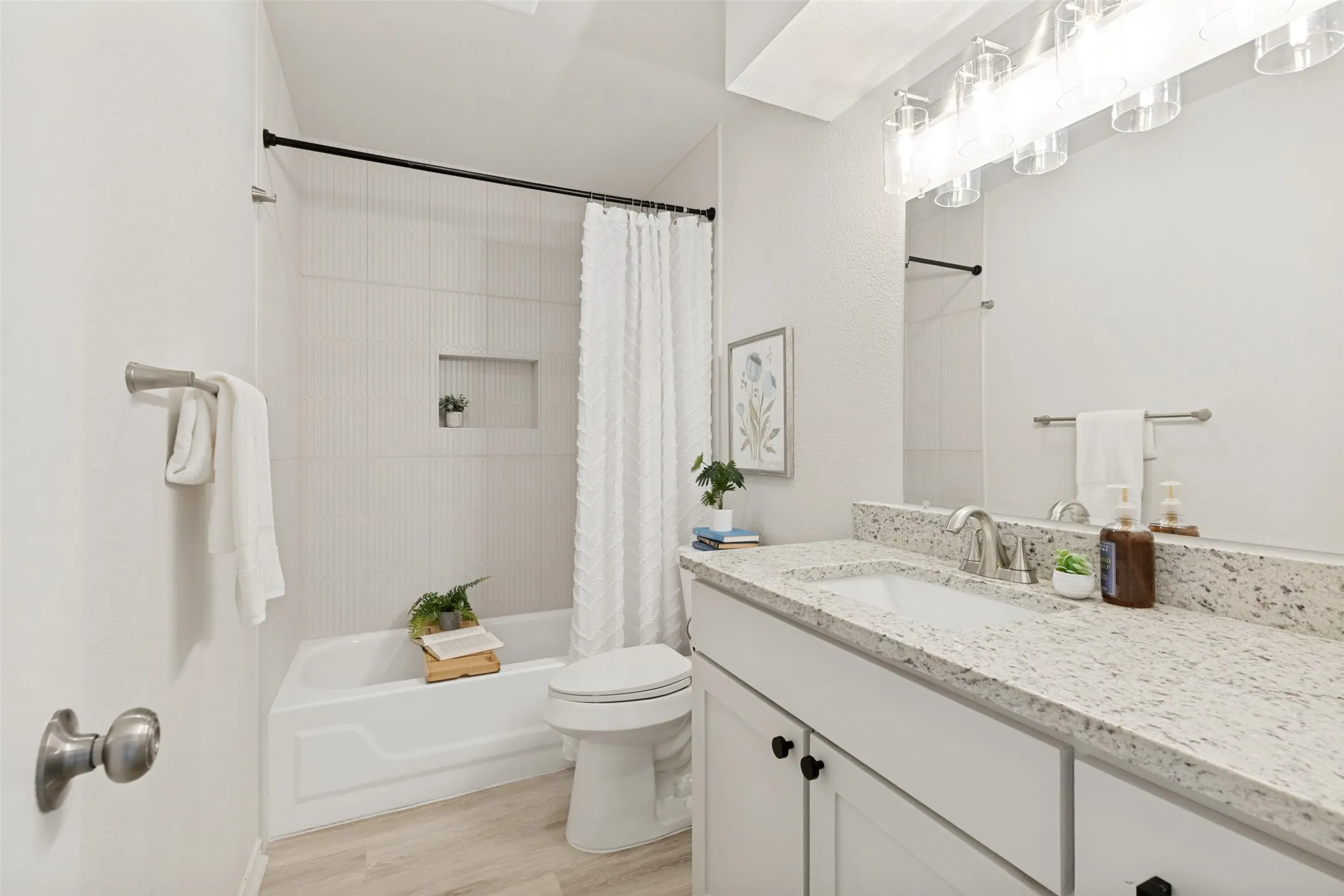 Full bathroom featuring a white vanity with a speckled countertop, a built-in sink, and under-sink cabinetry