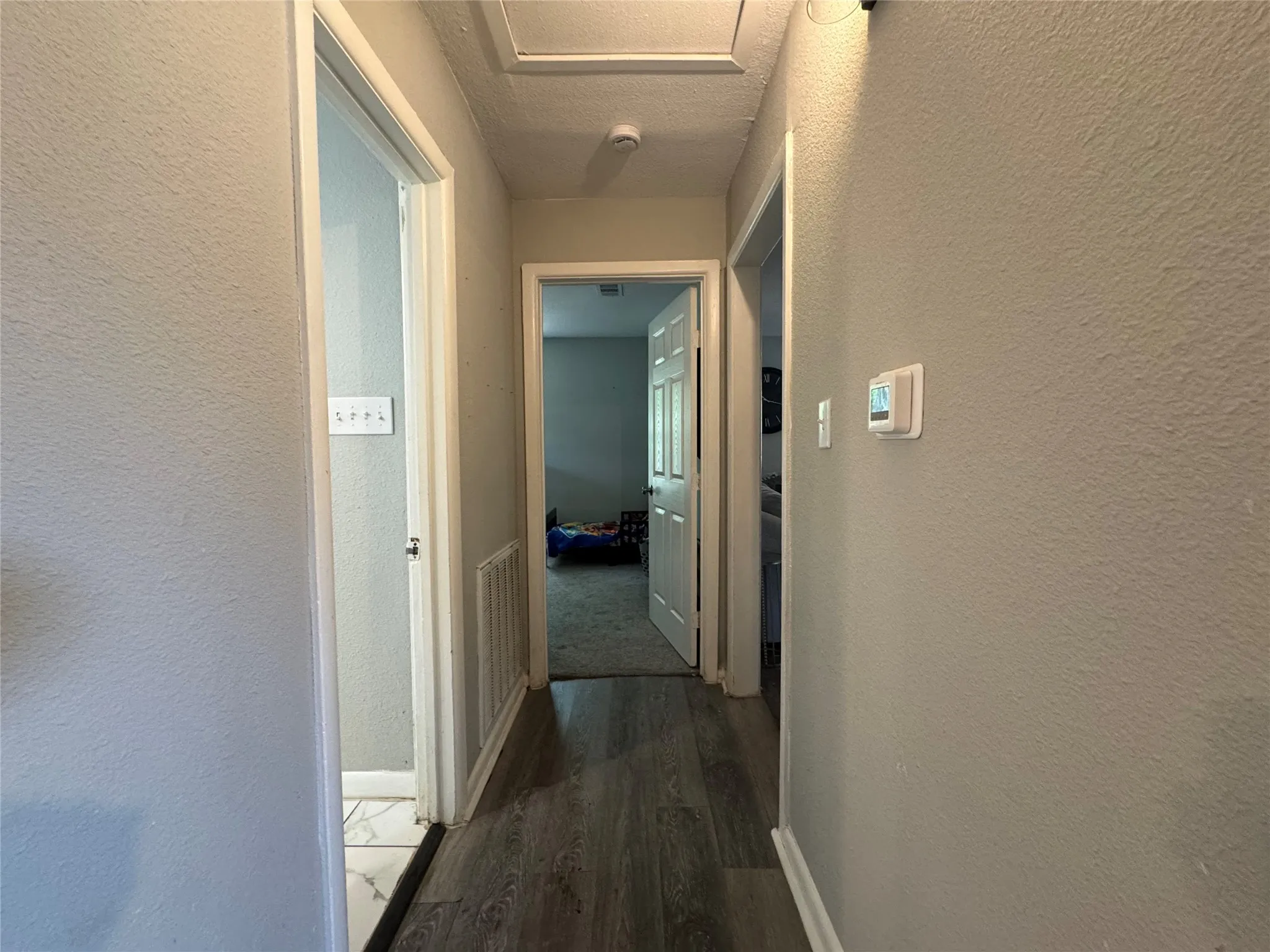 Hallway featuring wood-finish flooring, light grey walls, and white trim