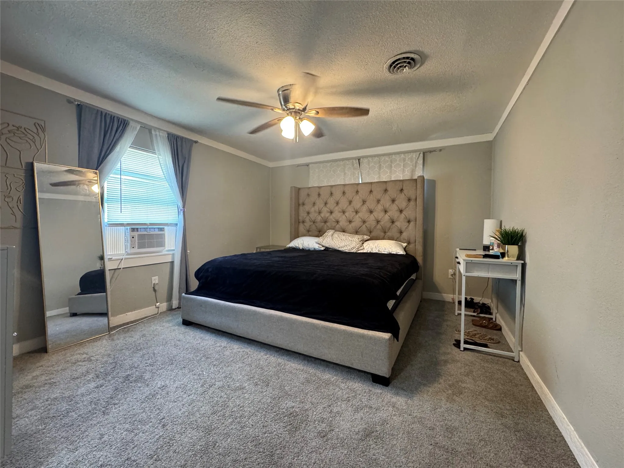Carpeted bedroom featuring neutral wall paint, crown molding, and a ceiling fan
