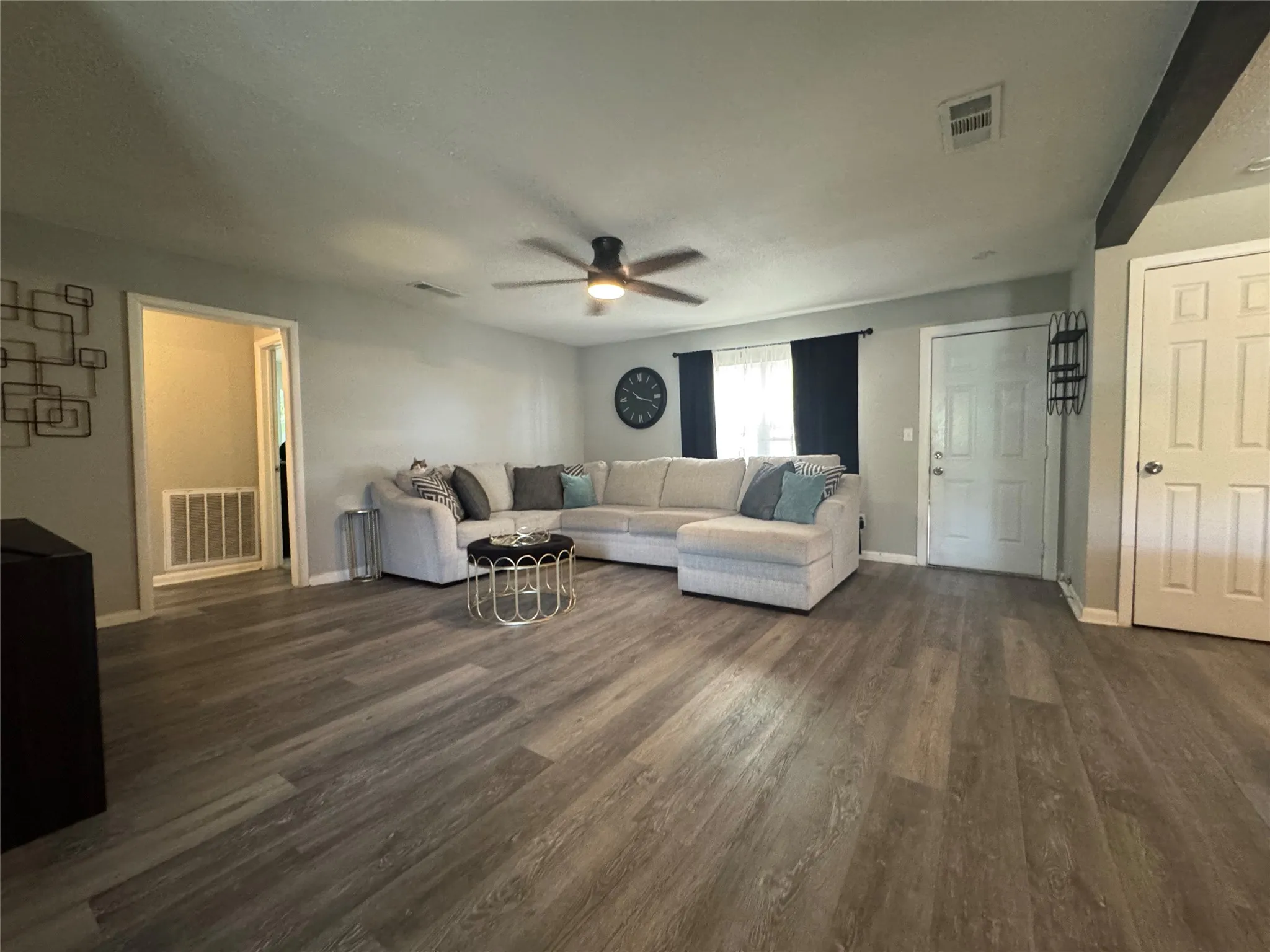 Spacious interior featuring wood-finish flooring, light grey wall tones, and a ceiling fan with integrated lighting