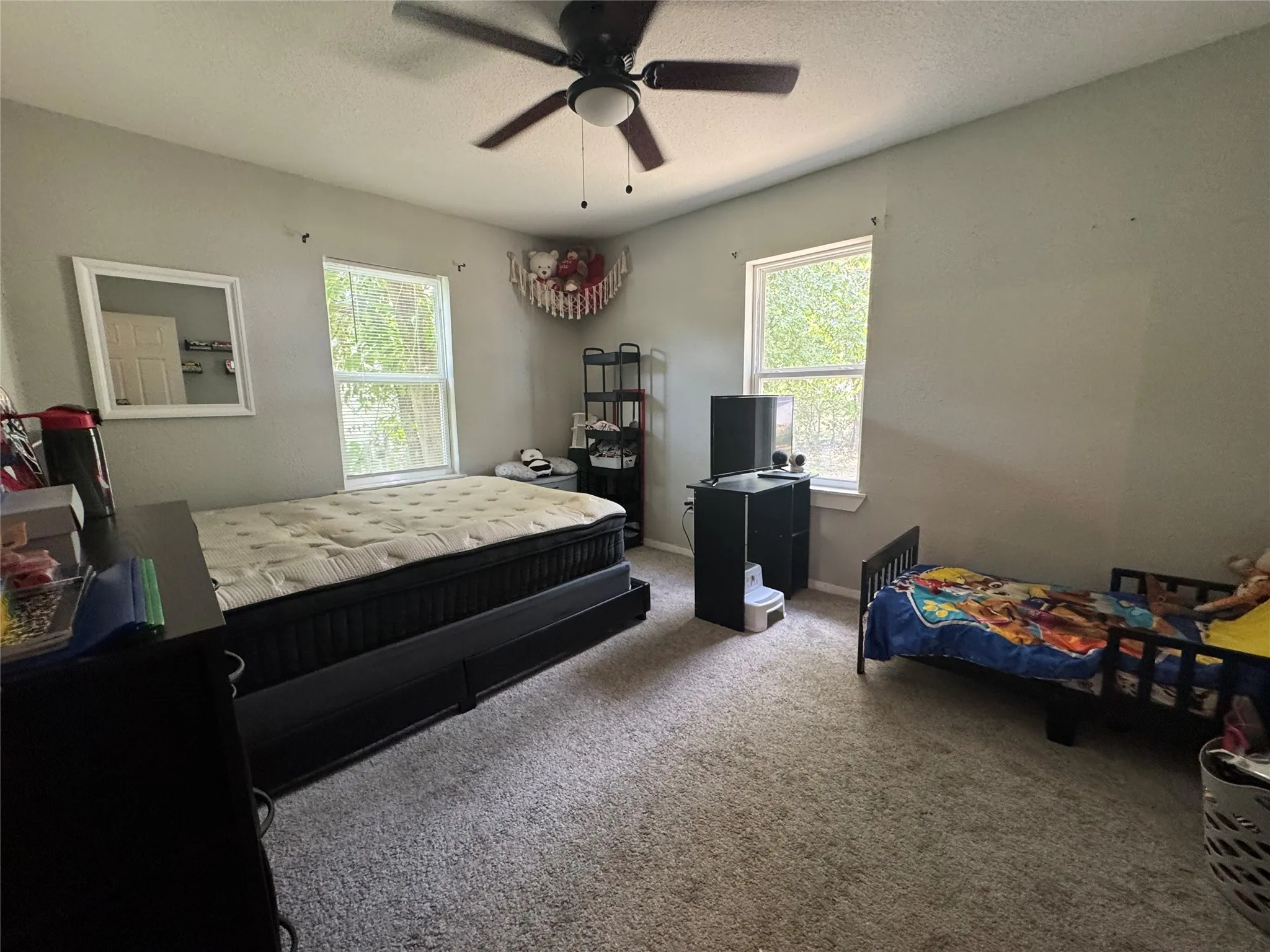 Spacious room featuring neutral carpeting and two window openings for natural light