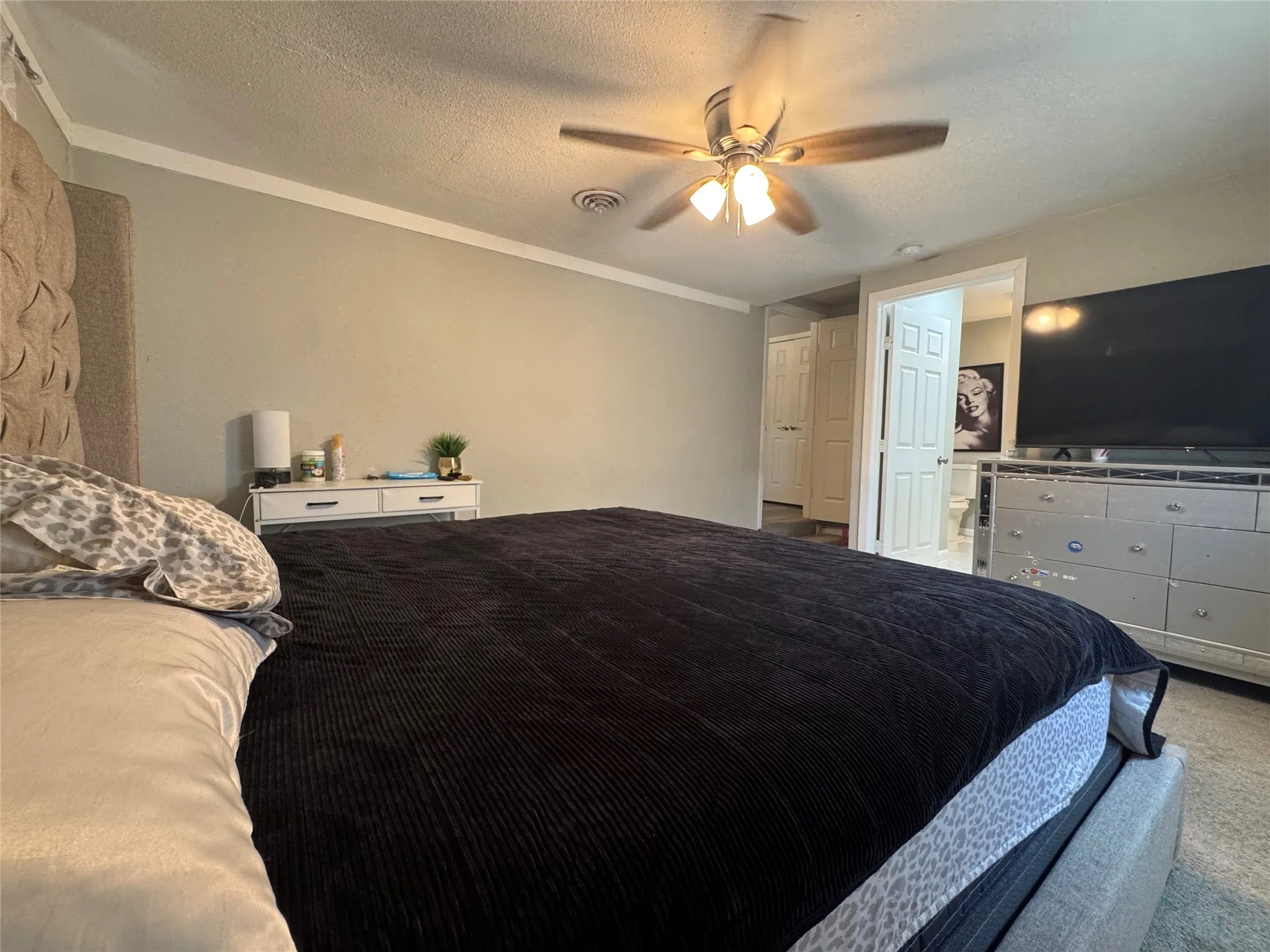 Bedroom featuring a ceiling fan with integrated lighting, crown molding, and neutral wall tones