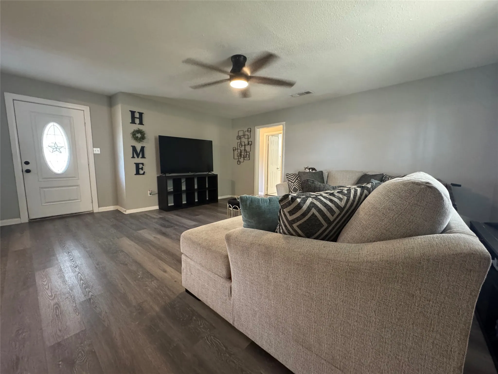 Living area featuring wood-finish flooring, a ceiling fan, and light gray wall paint