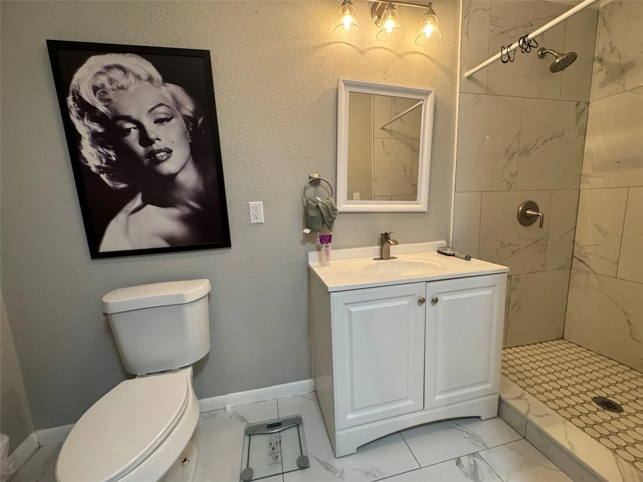 Bathroom featuring a white vanity with integrated sink, brushed nickel faucet, and overhead three-bulb vanity lighting