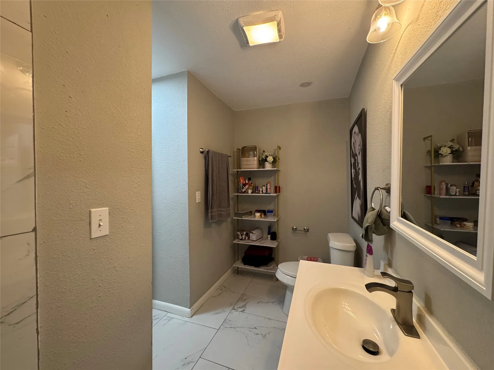 Bathroom featuring a white vanity with an integrated sink, brushed nickel faucet, and a framed wall mirror