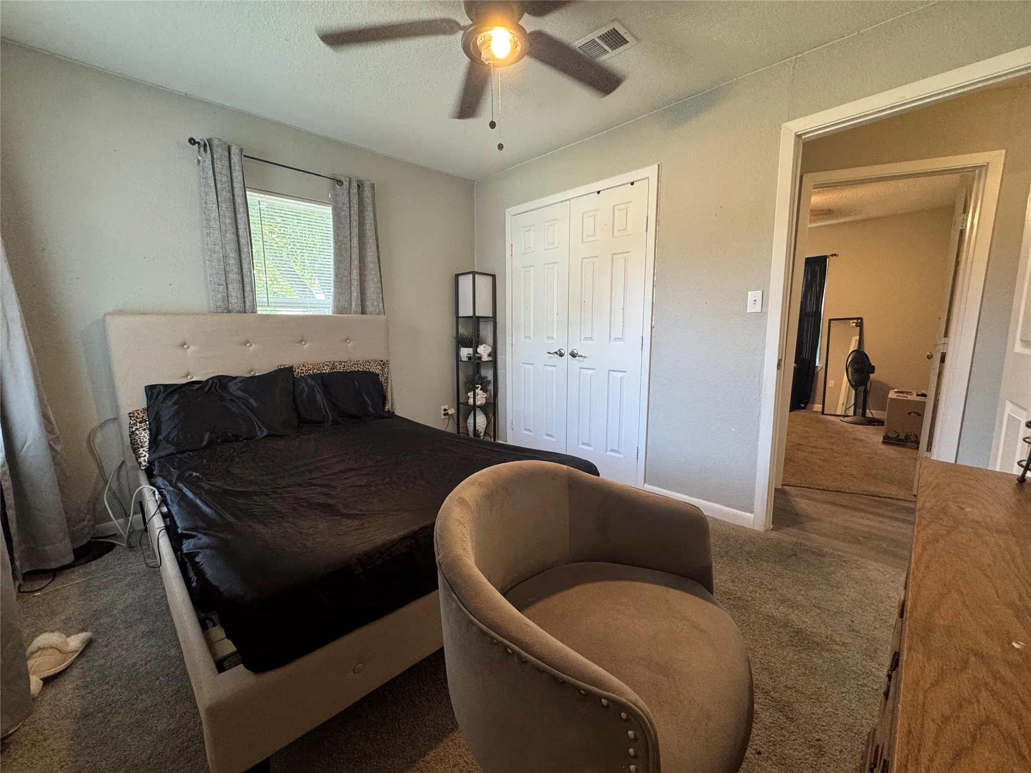 Carpeted room featuring a ceiling fan, a window with curtains, and a double-door closet with white paneled doors