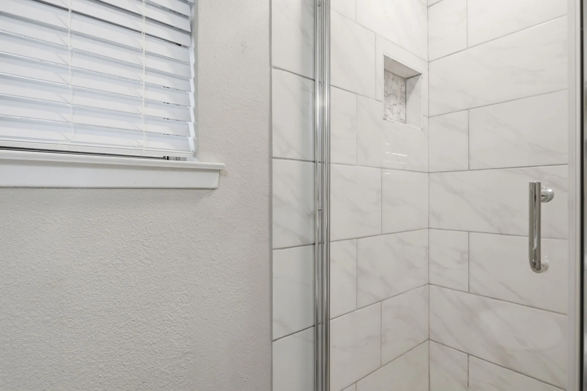 Walk in shower with a soap niche and glass door