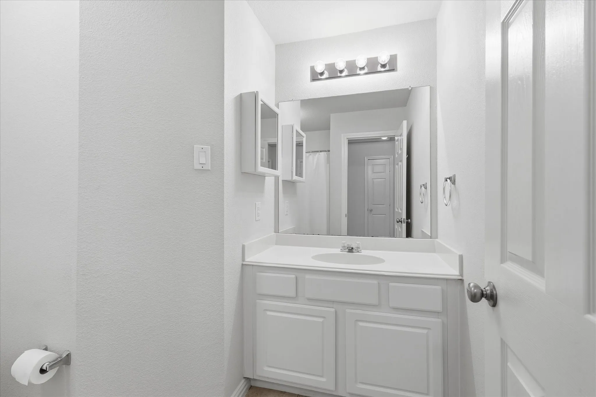Vanity area featuring a white countertop with an integrated sink, white cabinetry, and a large wall-mounted mirror