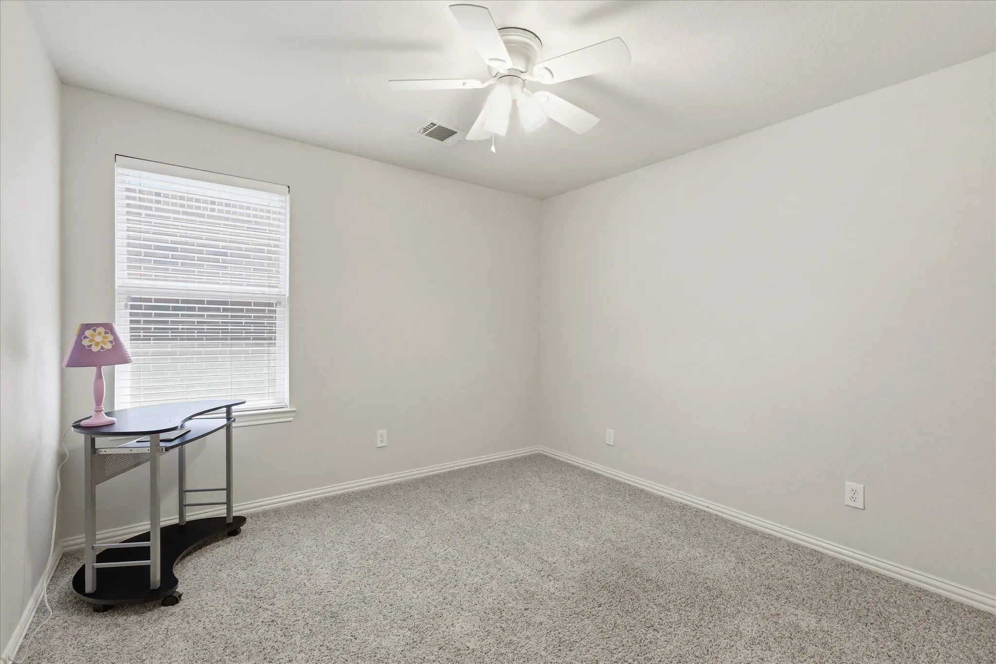 Neutral-toned room with plush carpeting and a white ceiling fan