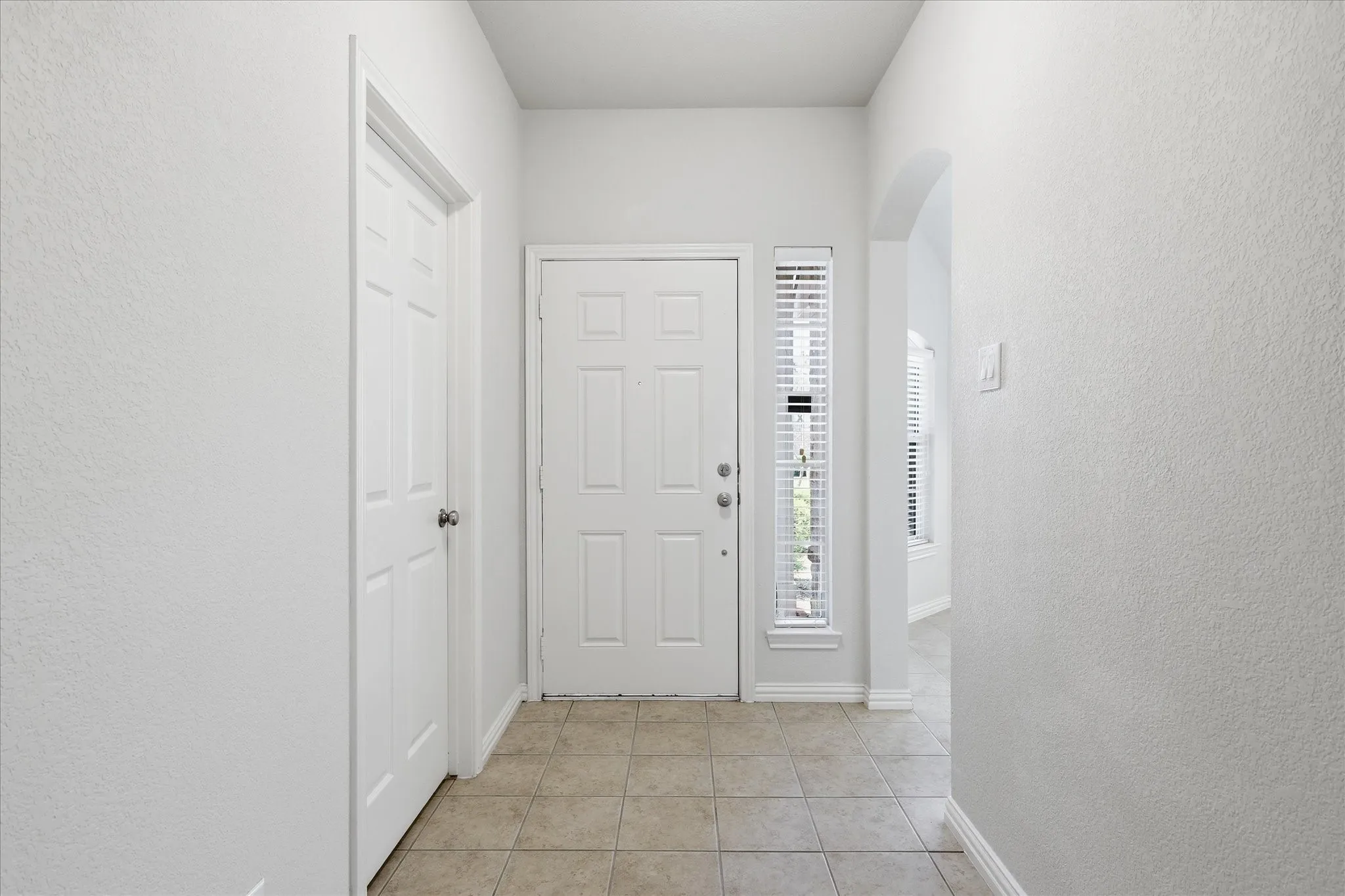 Entryway featuring a panel door, tile flooring, and a sidelight with blinds