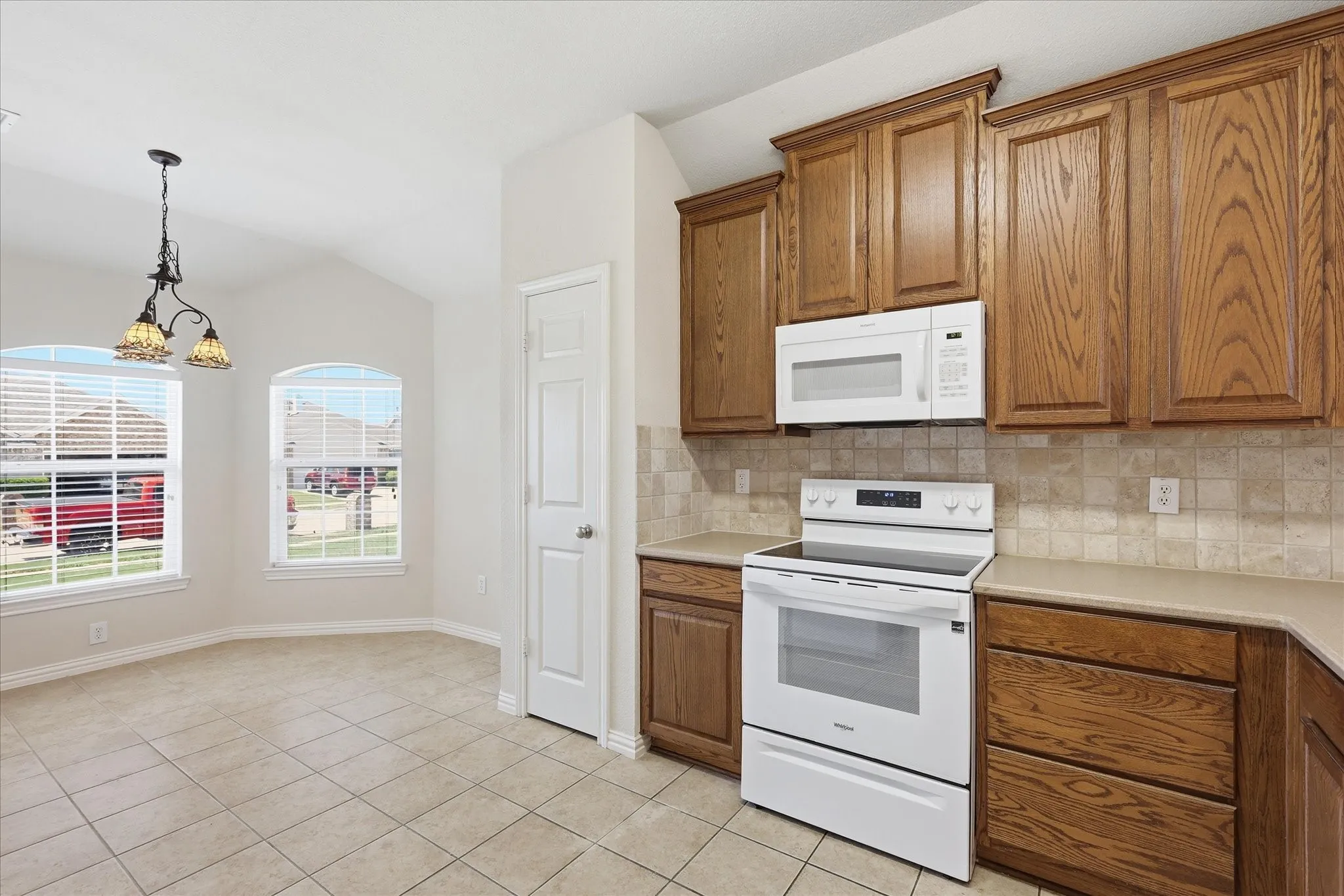 Kitchen and dining area featuring wood cabinetry, white appliances, and tiled flooring
