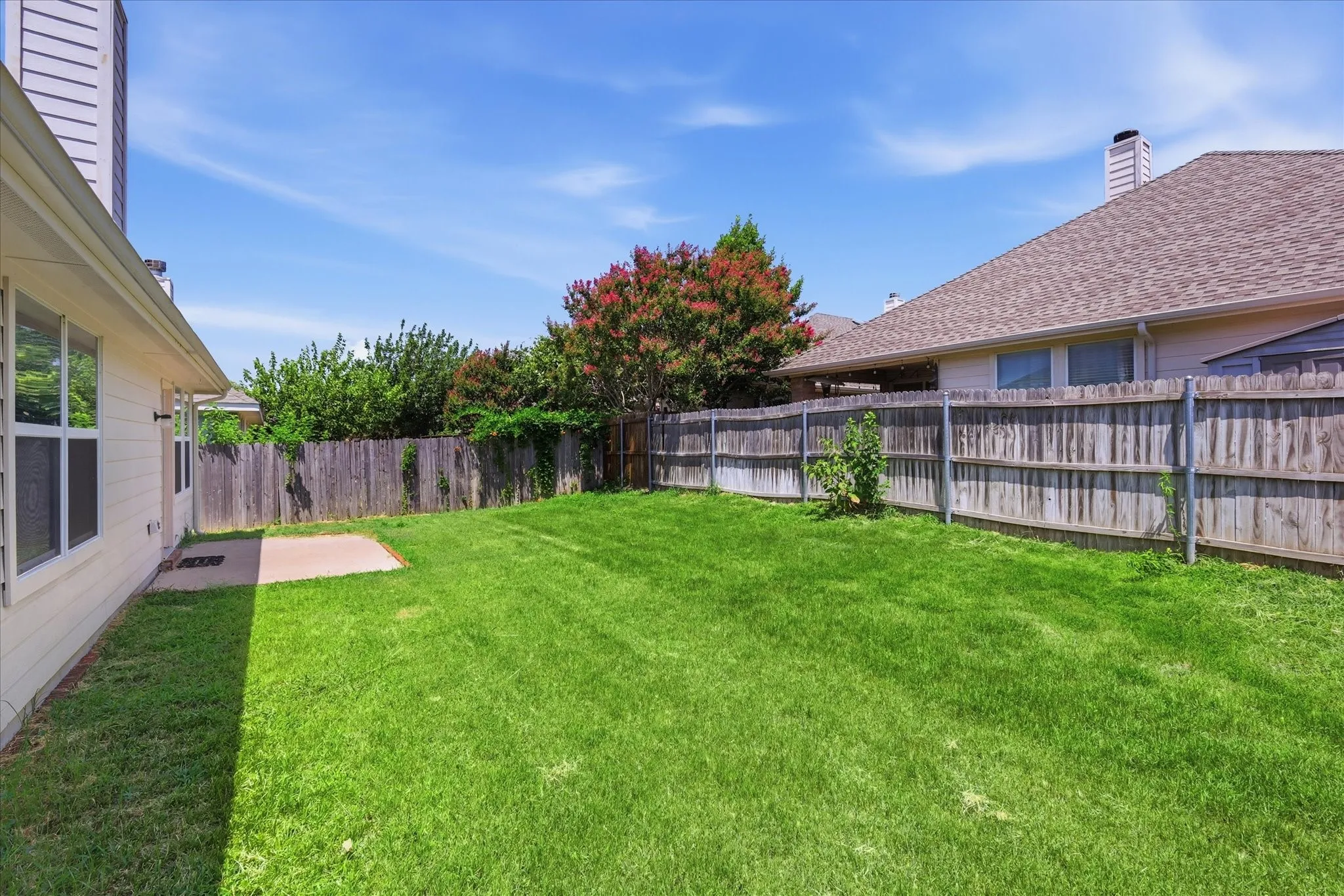 Expansive green lawn with a wood privacy fence