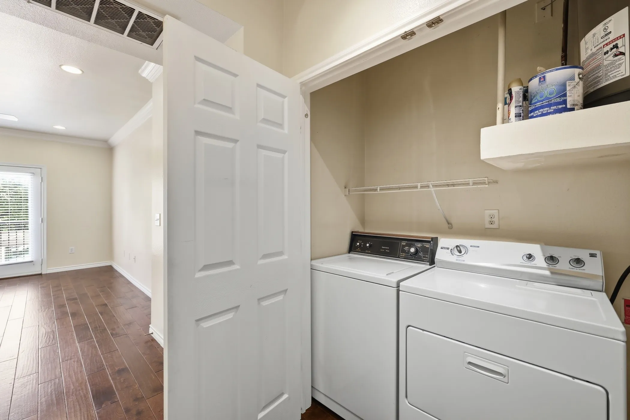 Dedicated laundry closet featuring a washer and dryer, an overhead wire shelf, and an additional built-in shelf