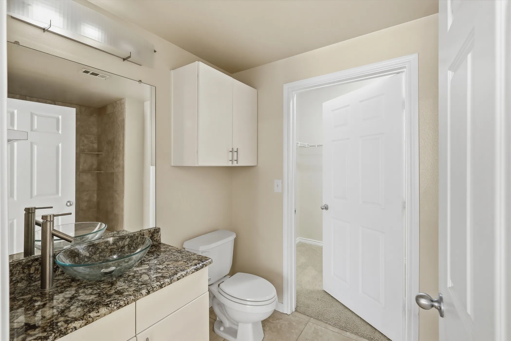 Bathroom featuring a glass vessel sink, single-handle faucet, granite-finish countertop, and tile flooring