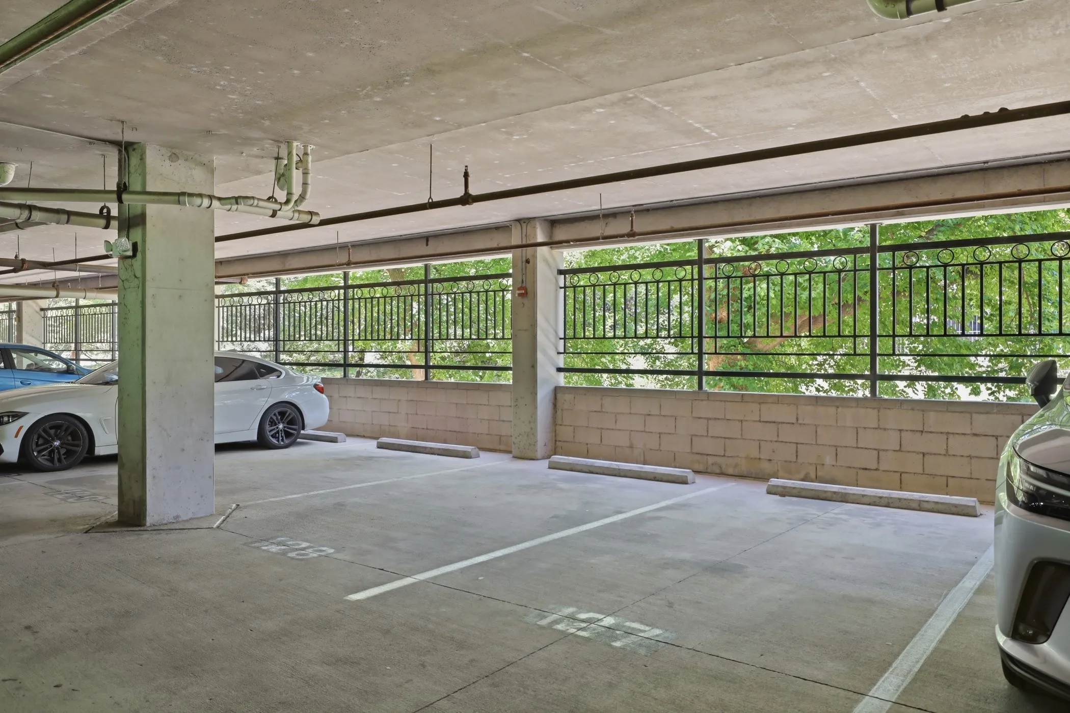Concrete parking garage featuring designated parking spaces with painted lines and wheel stops
