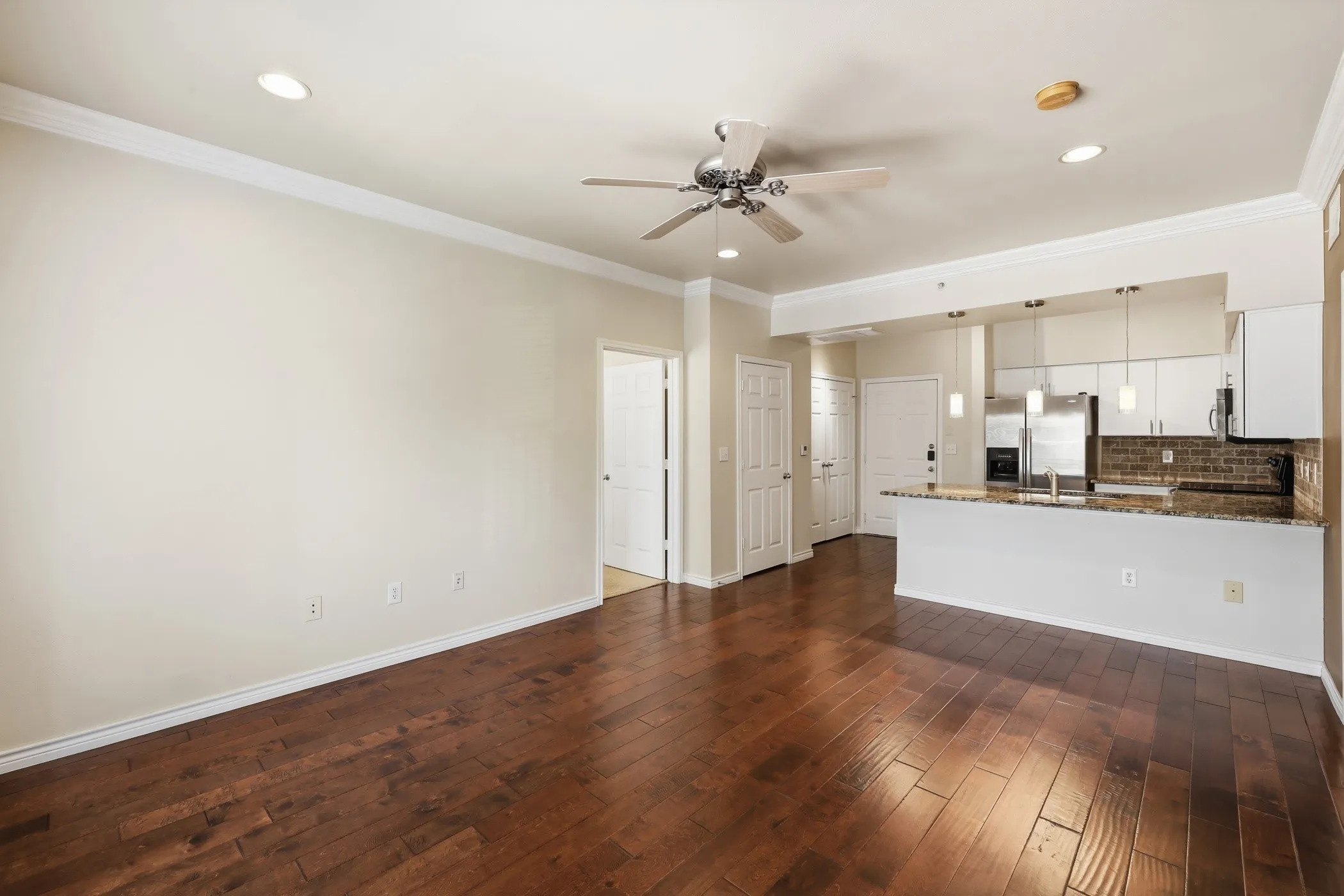 Open-concept living space featuring wood-finish flooring, recessed lighting, and a ceiling fan