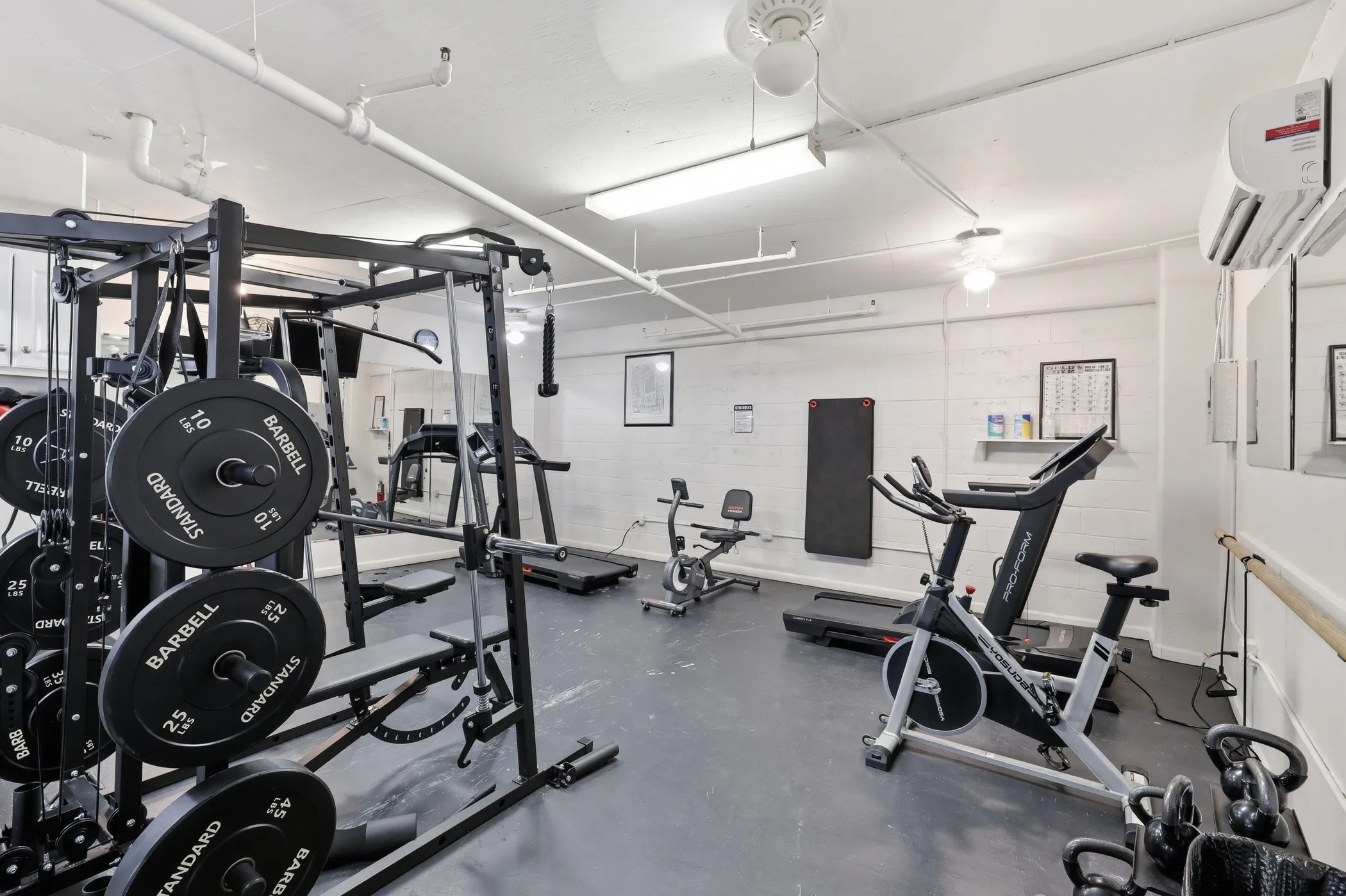 Dedicated fitness space featuring rubber flooring and white painted brick walls