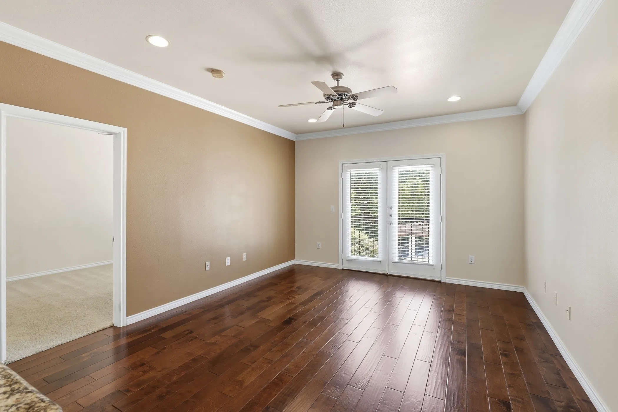 Spacious room featuring rich wood-finish flooring, recessed lighting, and crown molding