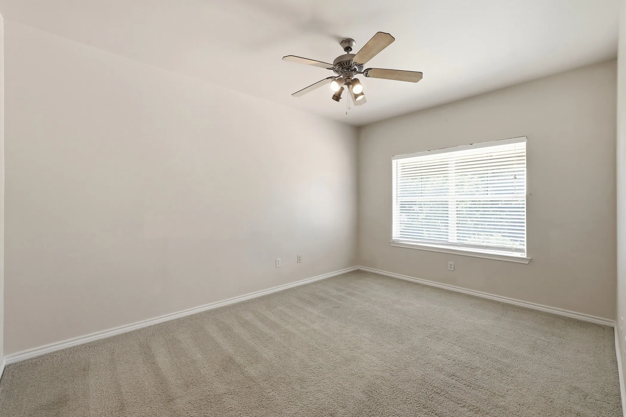 Carpeted room featuring a ceiling fan with integrated lighting, a window with horizontal blinds, and white baseboards