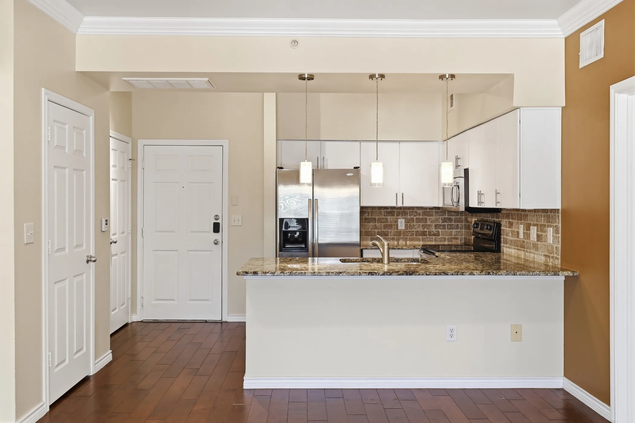 Kitchen featuring a breakfast bar with stone countertop, stainless steel appliances, white cabinetry, and a subway tile backsplash