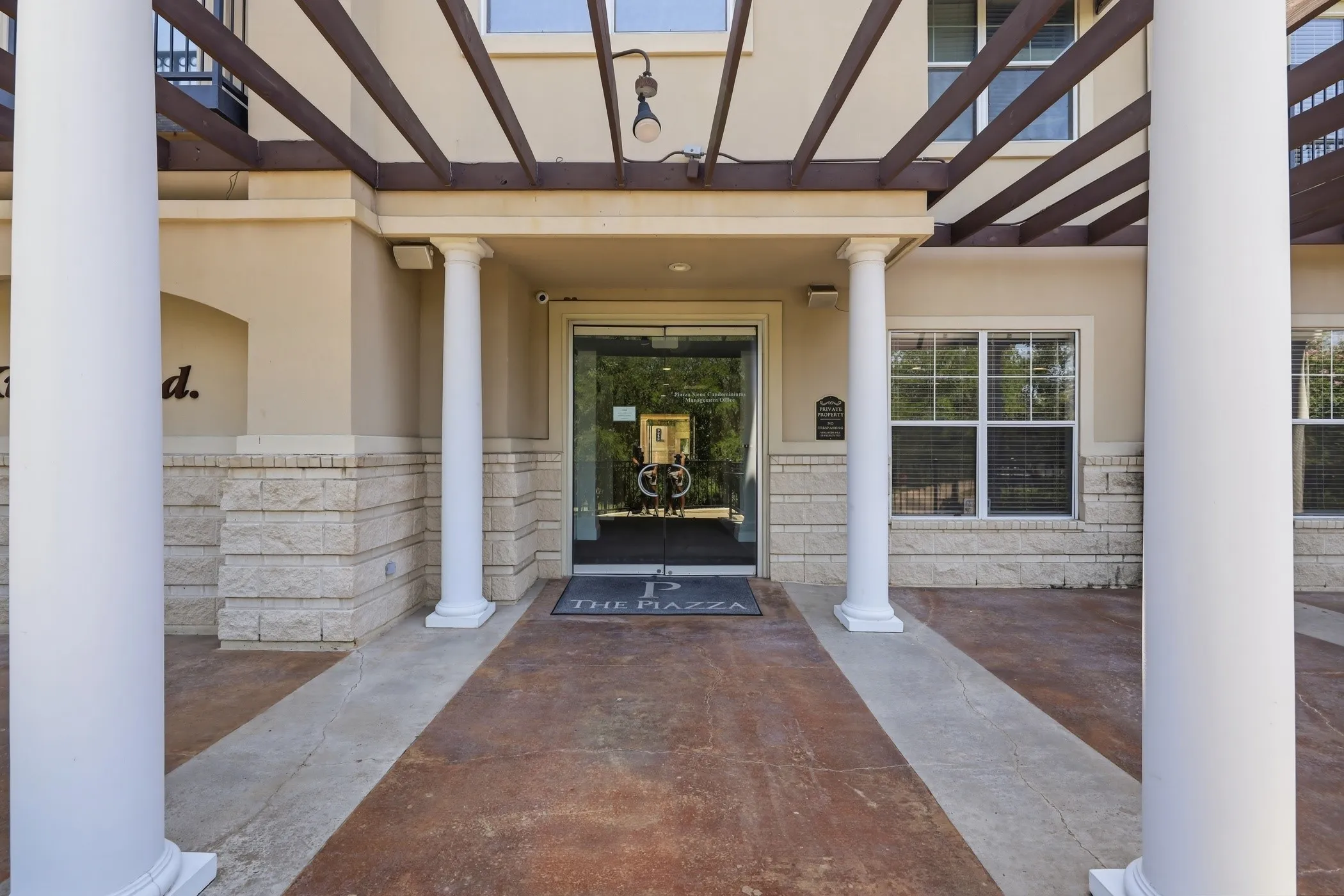 Inviting building entrance featuring classic white columns and a decorative pergola