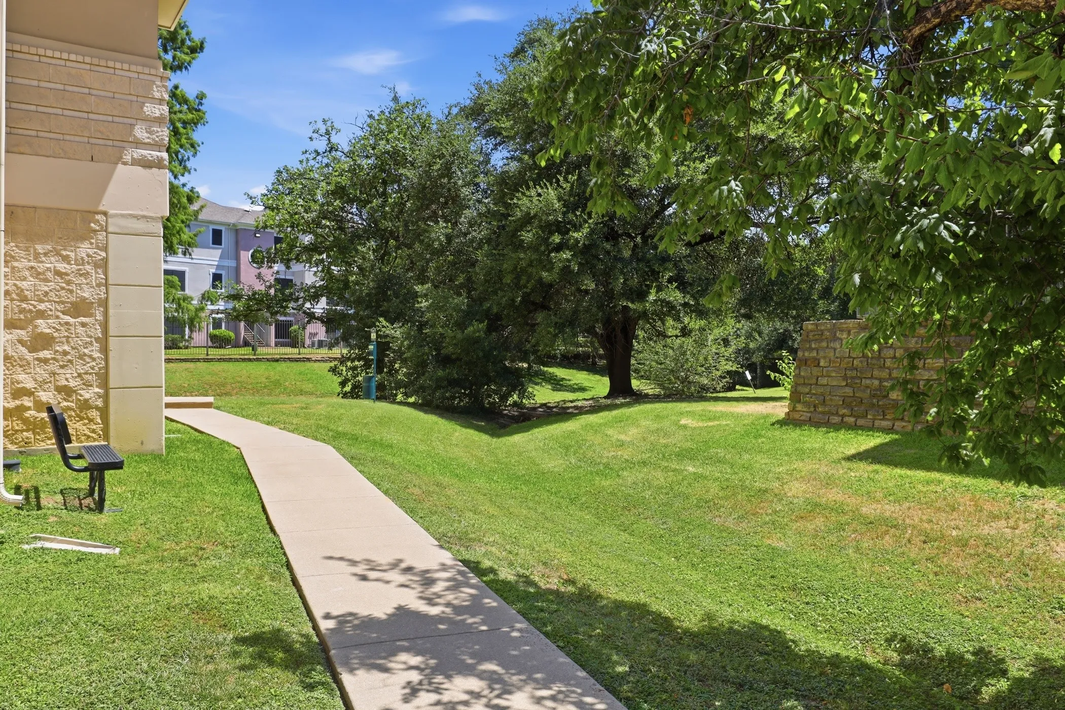 Expansive green space featuring mature trees and a stone retaining wall