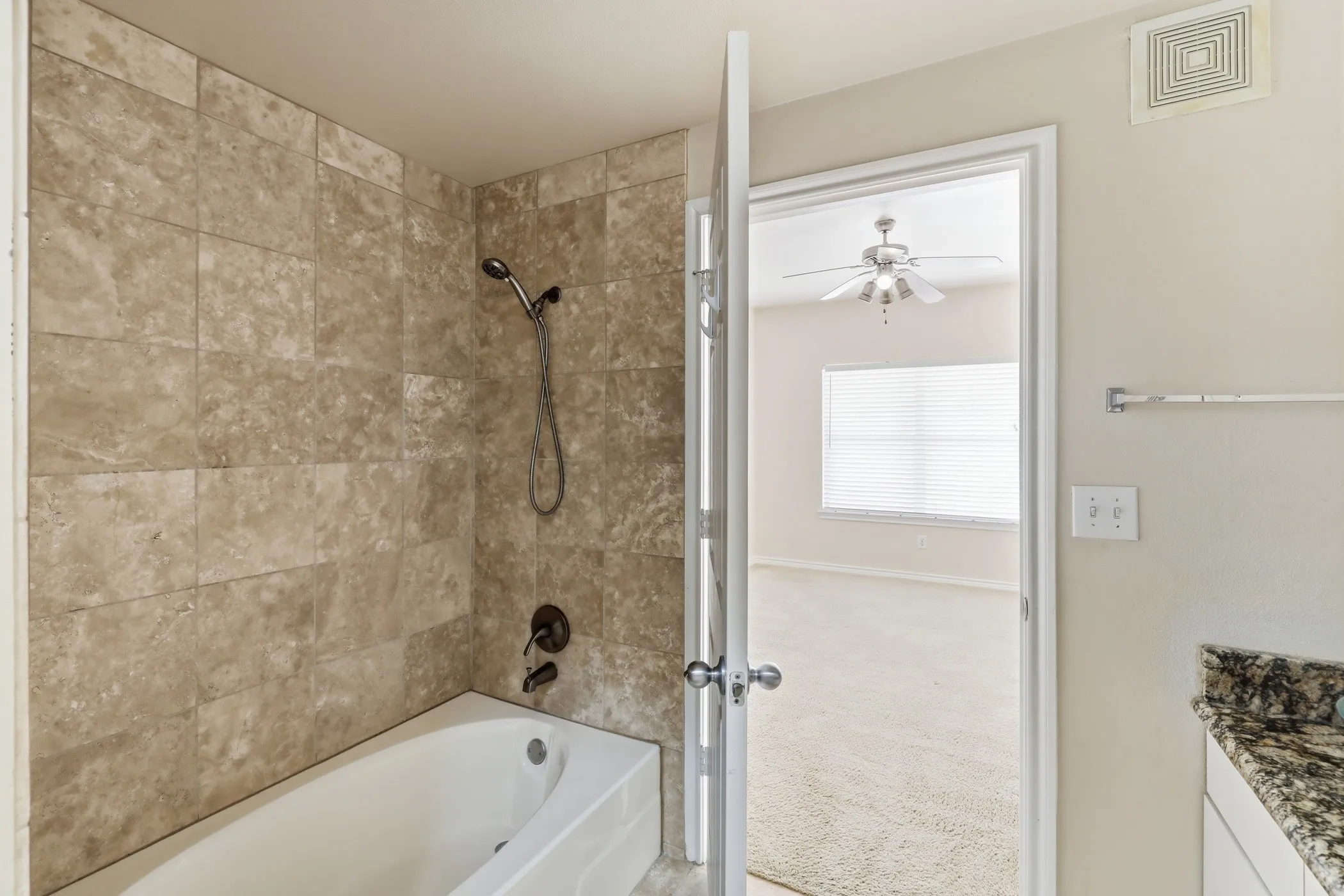 Bathtub with subway-style tiled surround and dark bronze fixtures