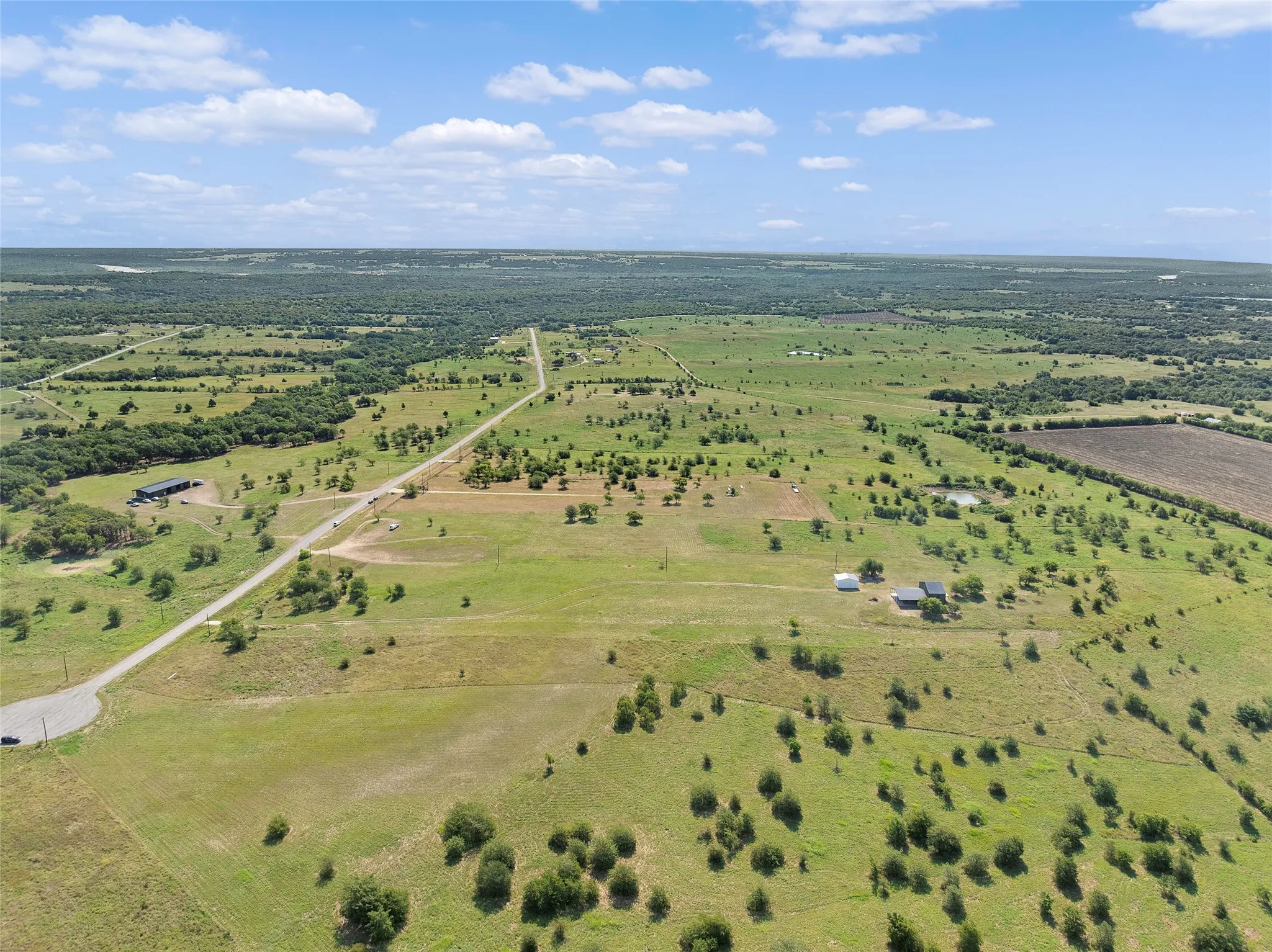 Expansive rural landscape featuring a long paved road traversing green pastures