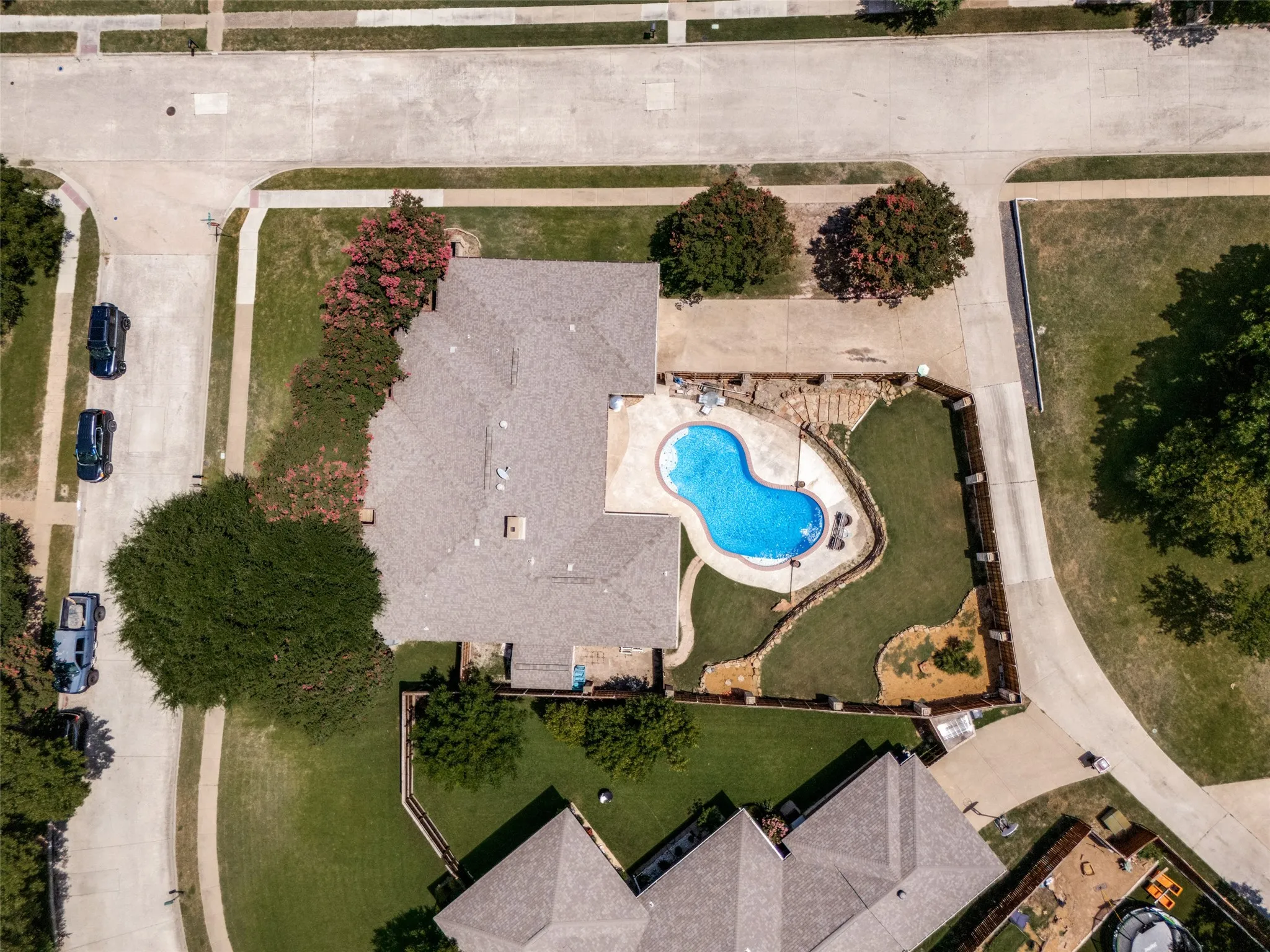 Kidney-shaped swimming pool with surrounding concrete patio and landscaping