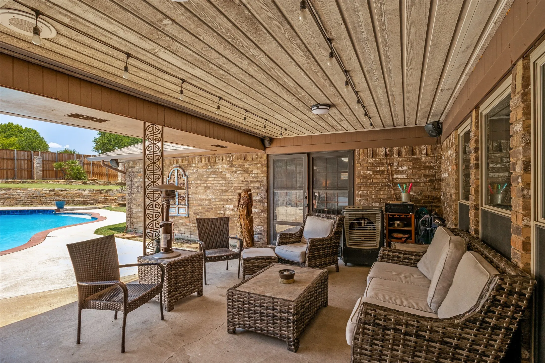 Covered patio featuring a wood-finish ceiling, in ceiling surround-sound speakers, French doors into primary bedroom and a brick exterior wall