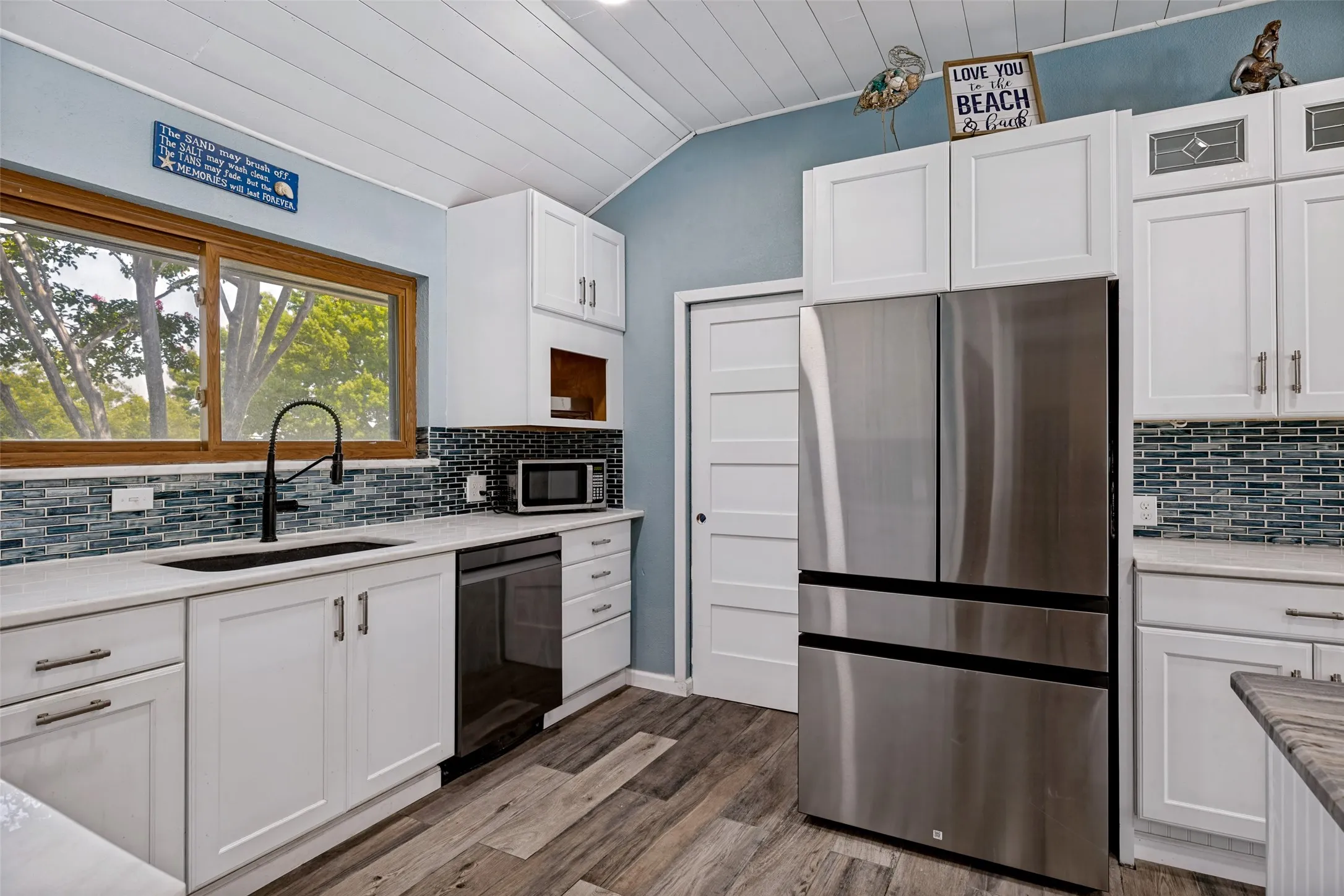 Modern kitchen featuring white shaker cabinetry, stainless steel refrigerator, and a tiled backsplash