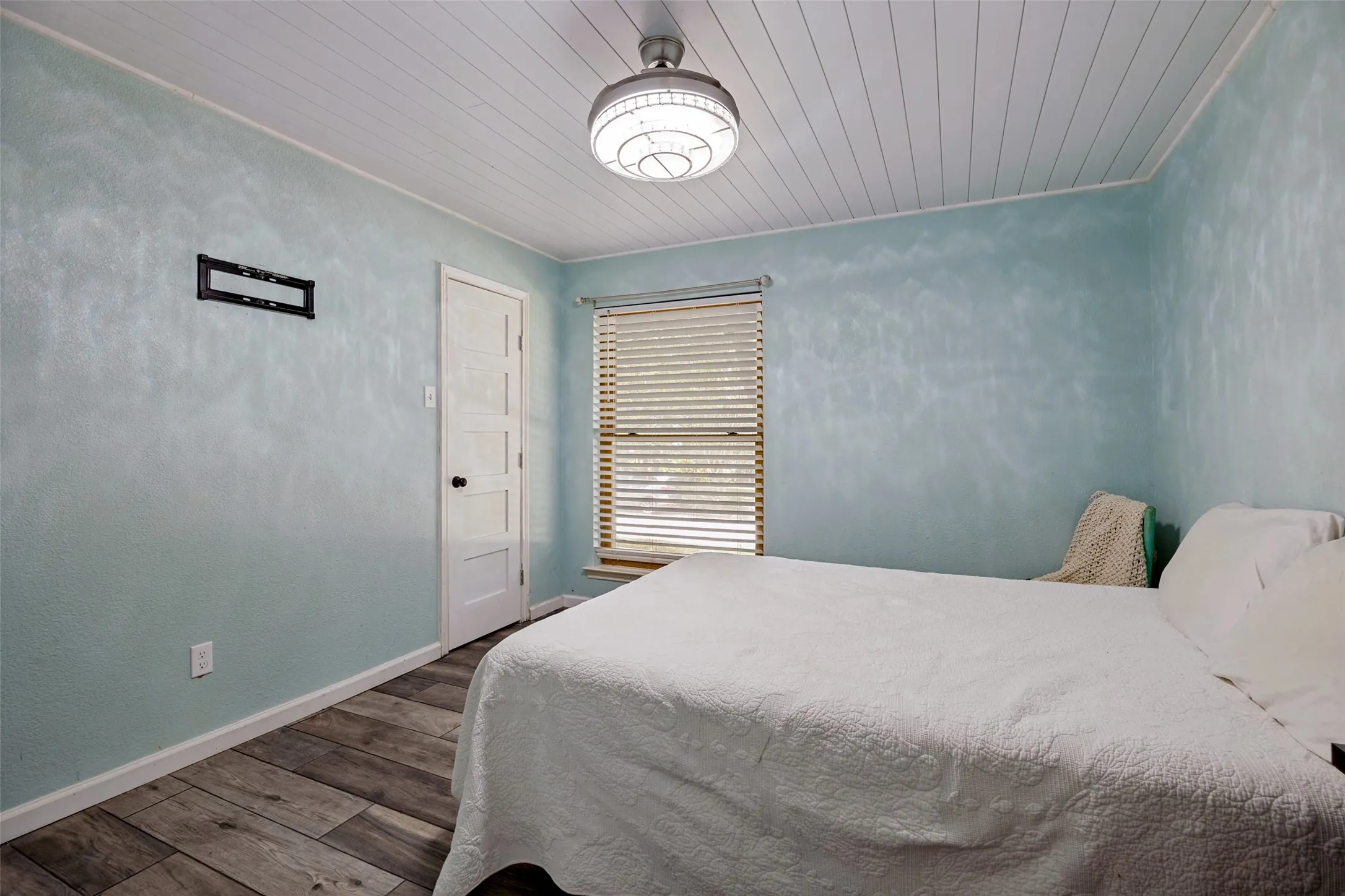 Room featuring wood-finish flooring, a paneled ceiling, and a window with blinds