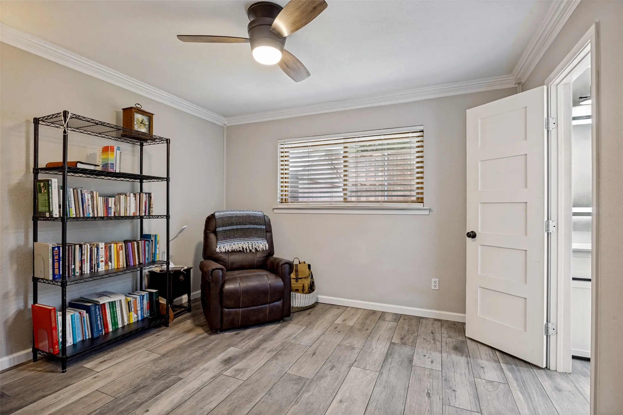 Room featuring wood-finish flooring, crown molding, and a ceiling fan with integrated lighting