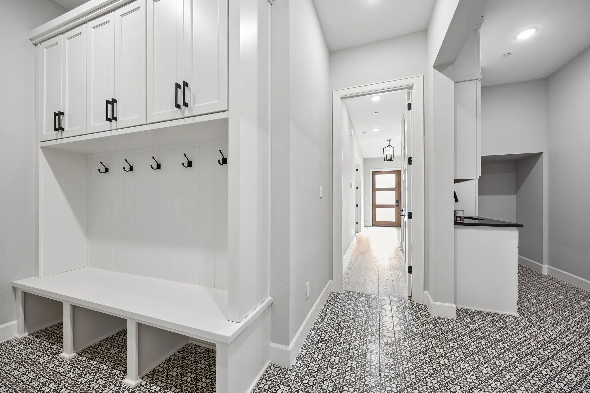 Built-in mudroom bench with upper cabinetry and black hardware