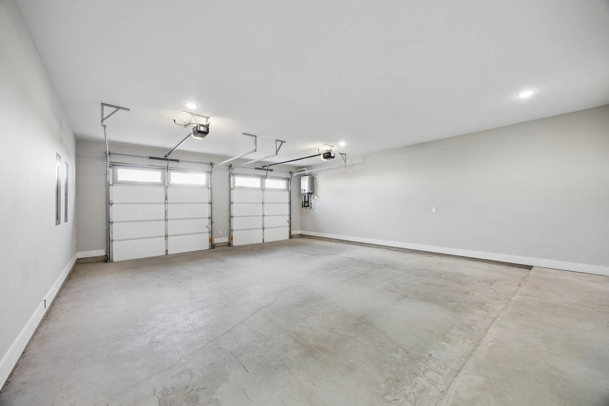 Spacious two-car garage featuring automatic openers, recessed lighting, and a concrete floor